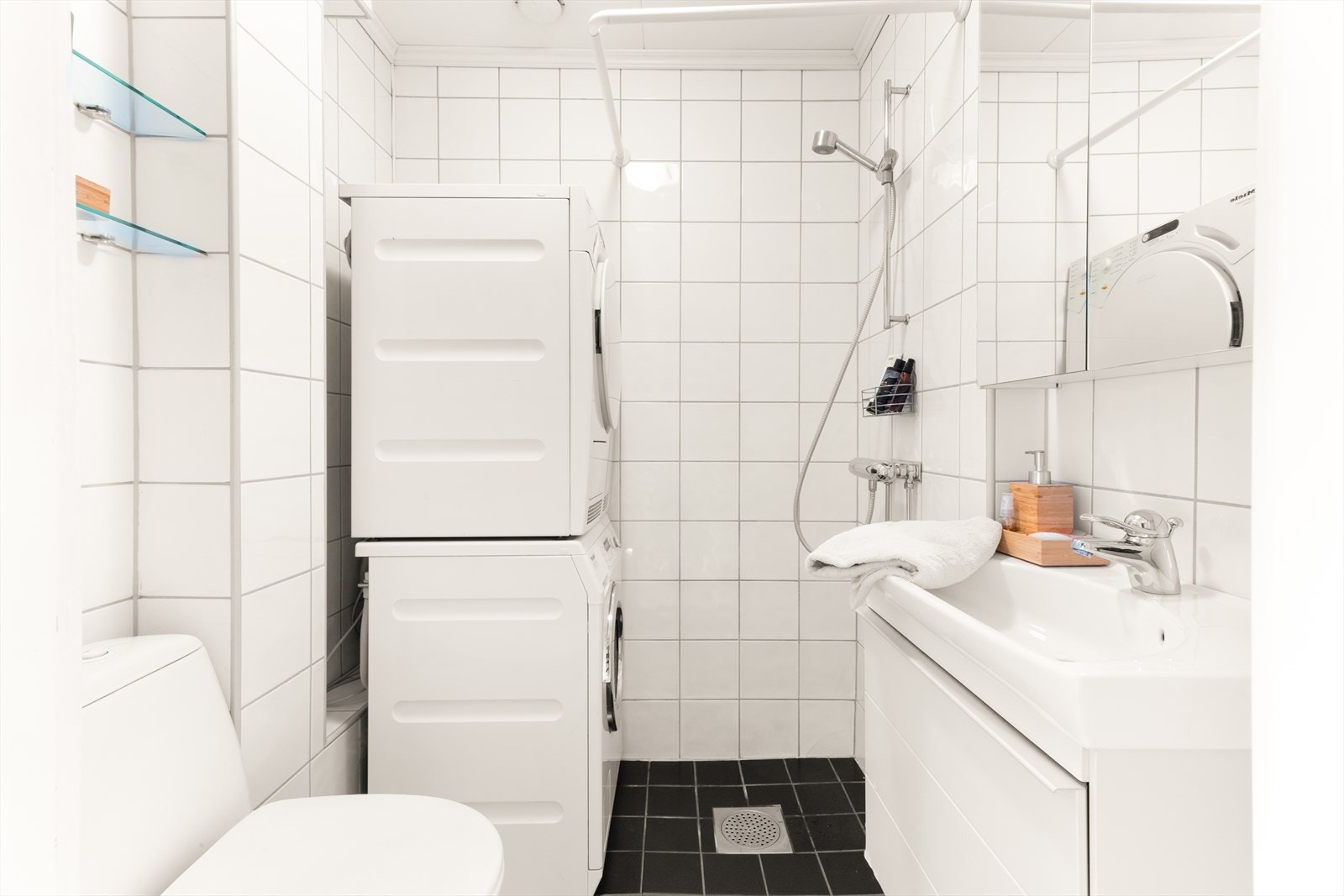 Pent flislagt baderom innredet med servantskap med folierte fronter, heldekkende servant og speilskap. Galleribilde