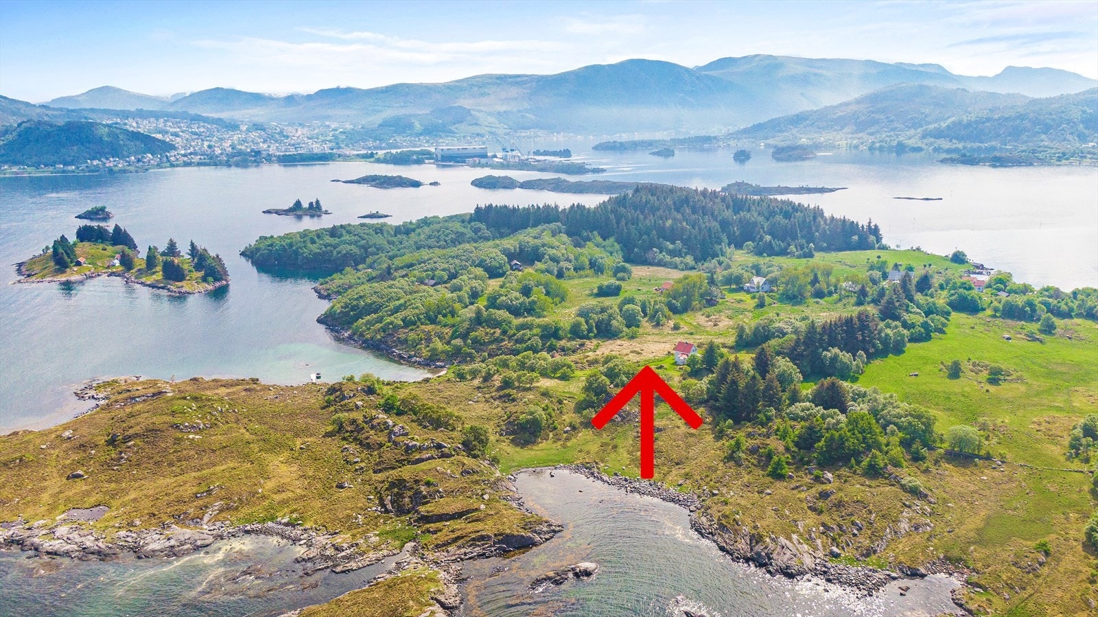 Eigedom markert med rød pil. Ulsteinvik kan skimtast i bakgrunnen. Galleribilde