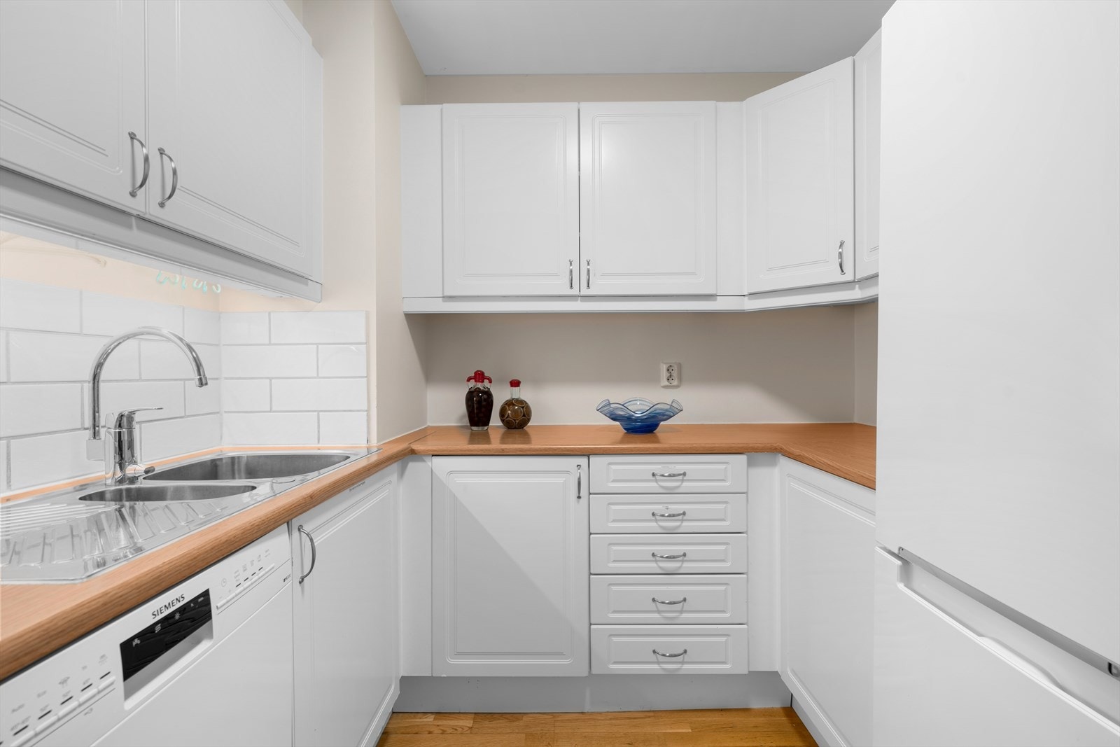 Kjøkkeninnredningen har hvite, profilerte fronter og laminat benkeplate. Galleribilde
