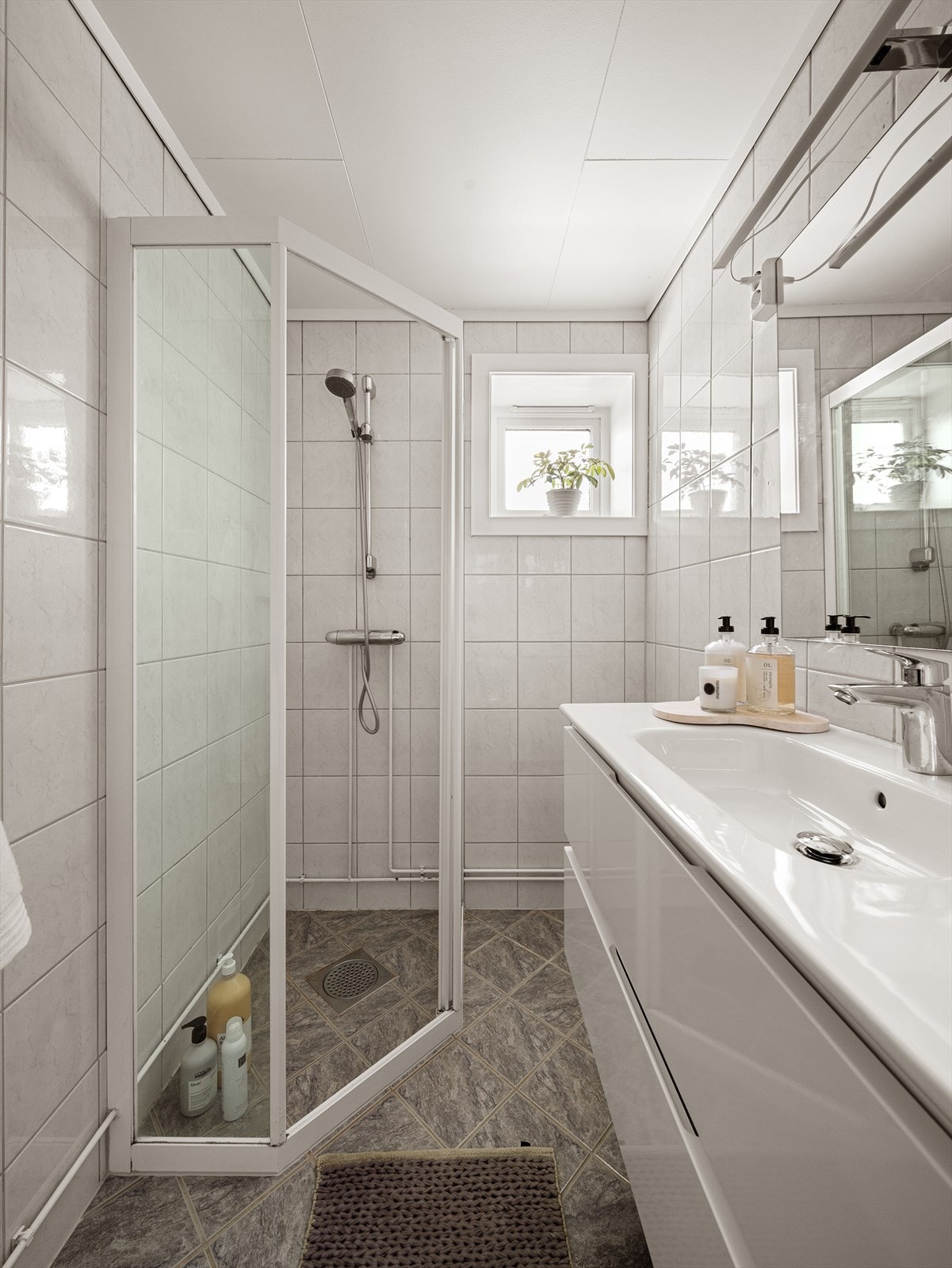 Her finner du dusjhjørne med tett sokkel og skyvedører i glass, vegghengt servantmøbel med oppbevaringsplass, speil med belysning, dobbel stikkontakt samt toalett. Galleribilde