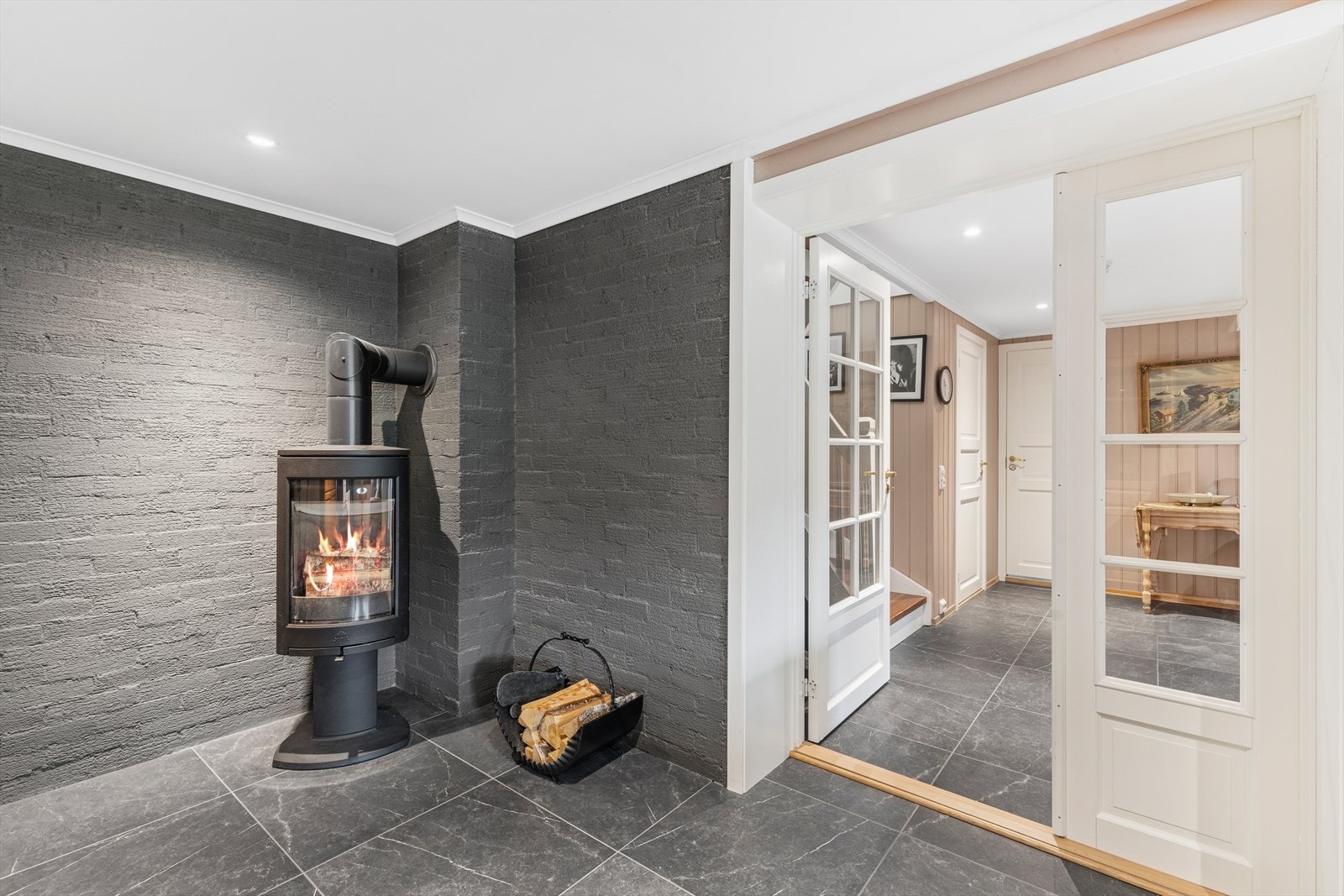 Det er en frittstående vedovn i kjellerstuen med glassfelt i dør. Denne er ekstra fin å ha på de litt kjøligere dagene! Galleribilde