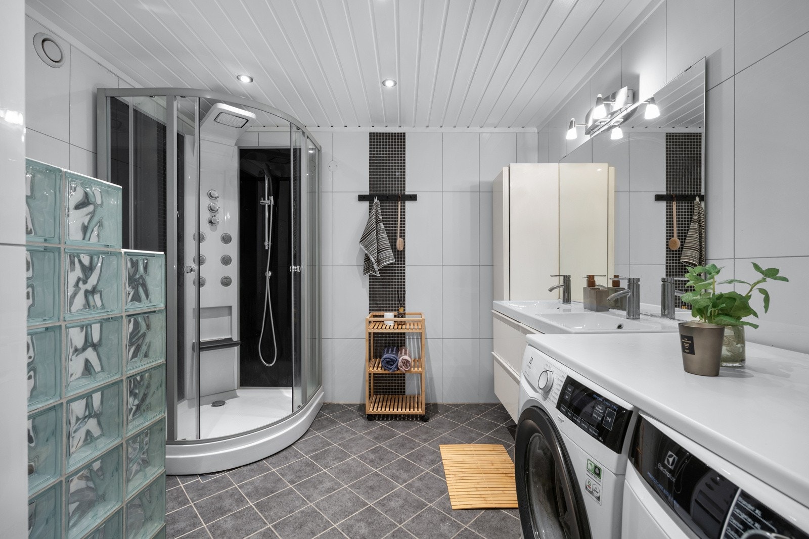 Romslig bad med lyse fliser på vegg og mørke fliser på gulv Galleribilde