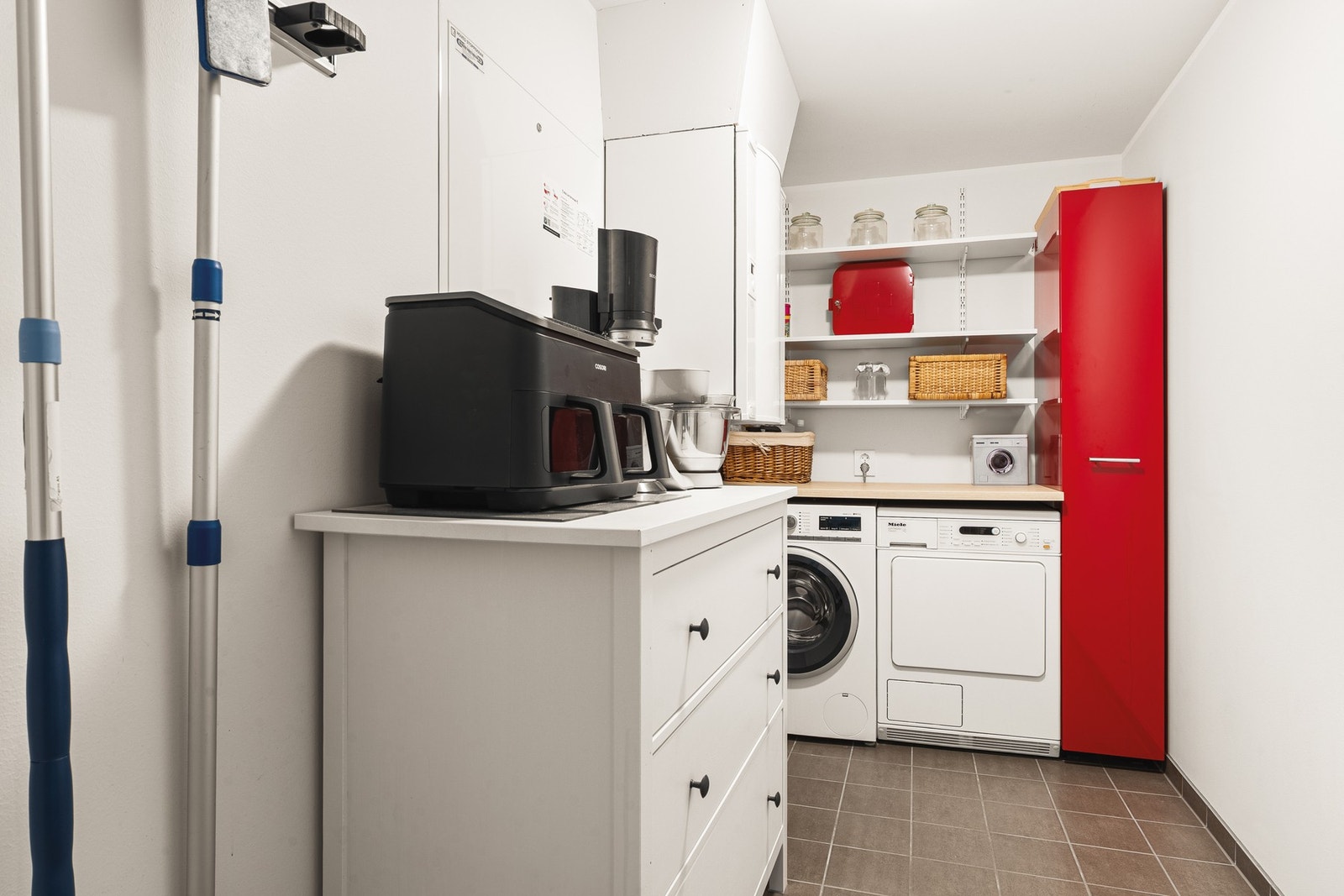 Separat vaskerom med plass til både vaskemaskin og tørketrommel. Rødt skap følger ikke med i handelen. Galleribilde