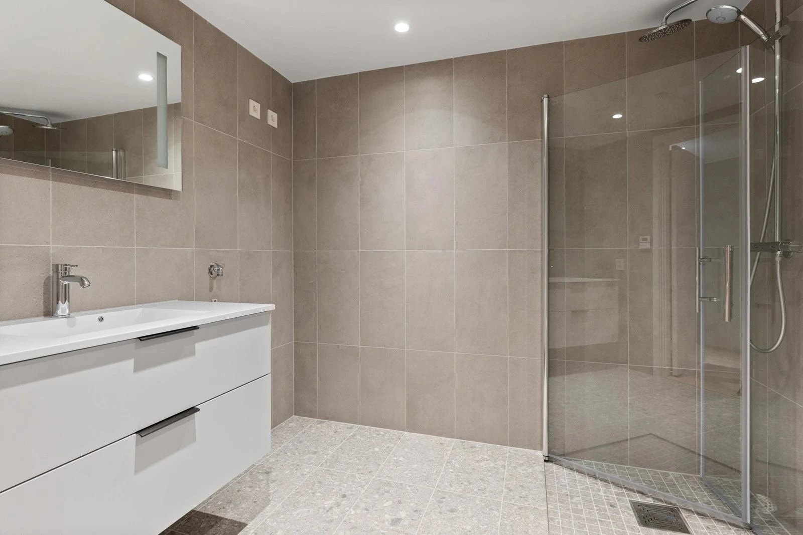 Romslig, flislagt bad med nedsenket dusjsone og god plass til vaskemaskin og tørketrommel Galleribilde