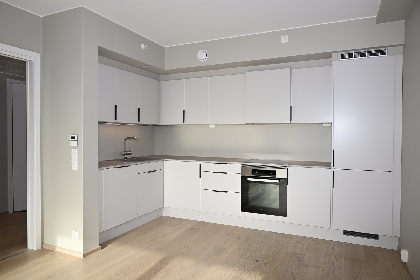 Kjøkkeninnredning fra Sigdal med integrerte hvitevarer fra Miele, Røroshetta ventilator og kjøkkenbatteri fra Grohe Galleribilde