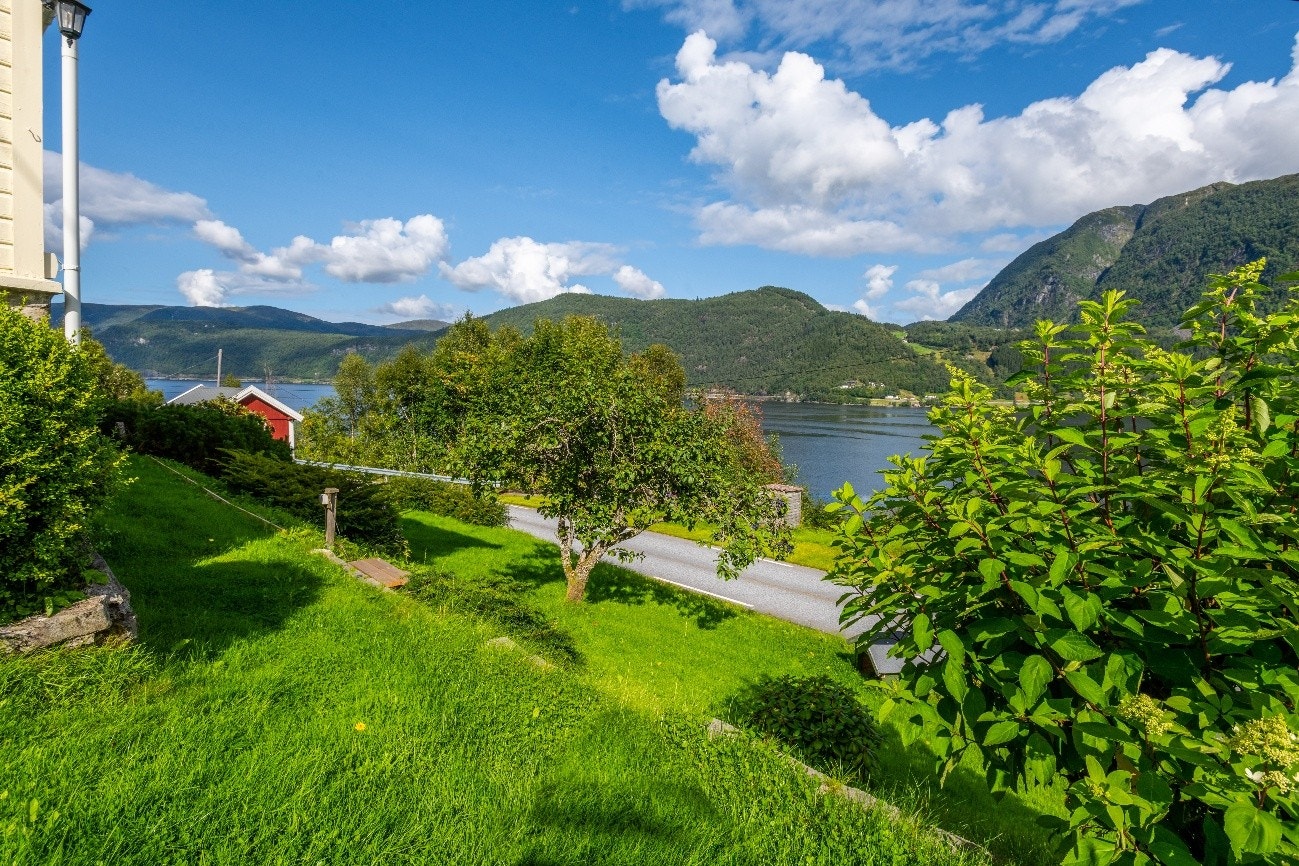 Rundt bustaden er det flott opparbeidd med murar, plen, frukttre og beplantning Galleribilde