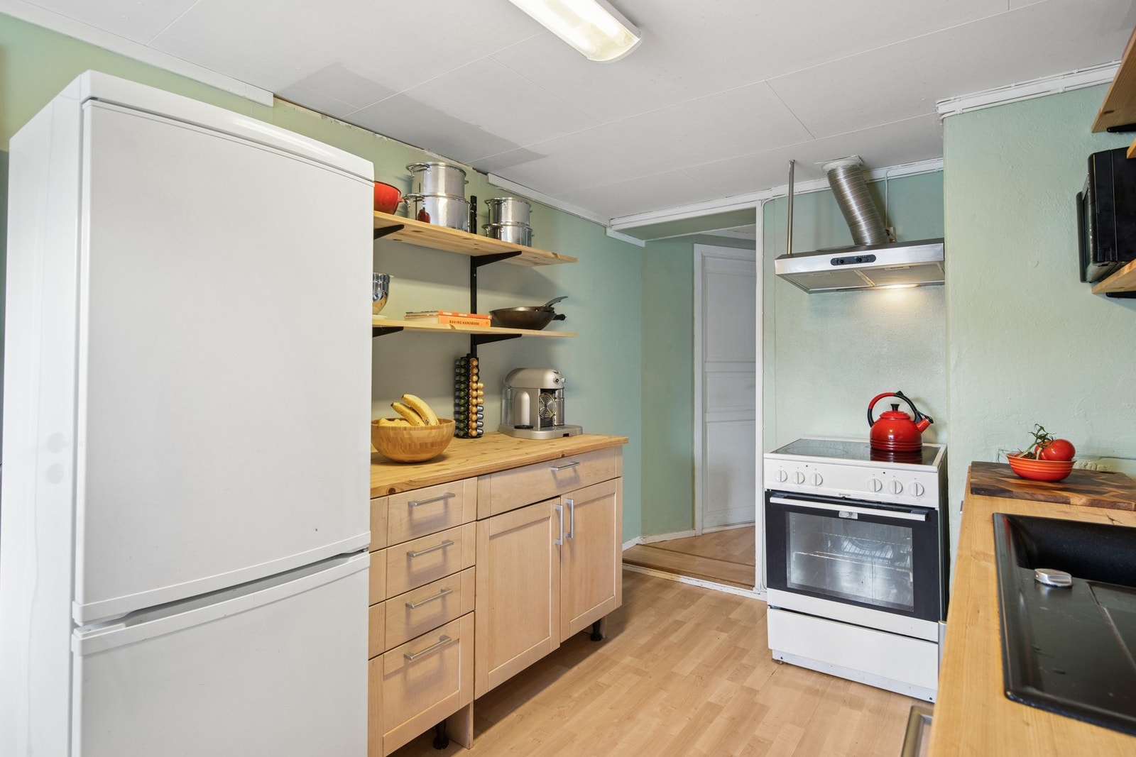 Kjøkkenet er innredet med åpne hyller og benkeflate i heltre. Her er det plass til både matlaging og lagring Galleribilde