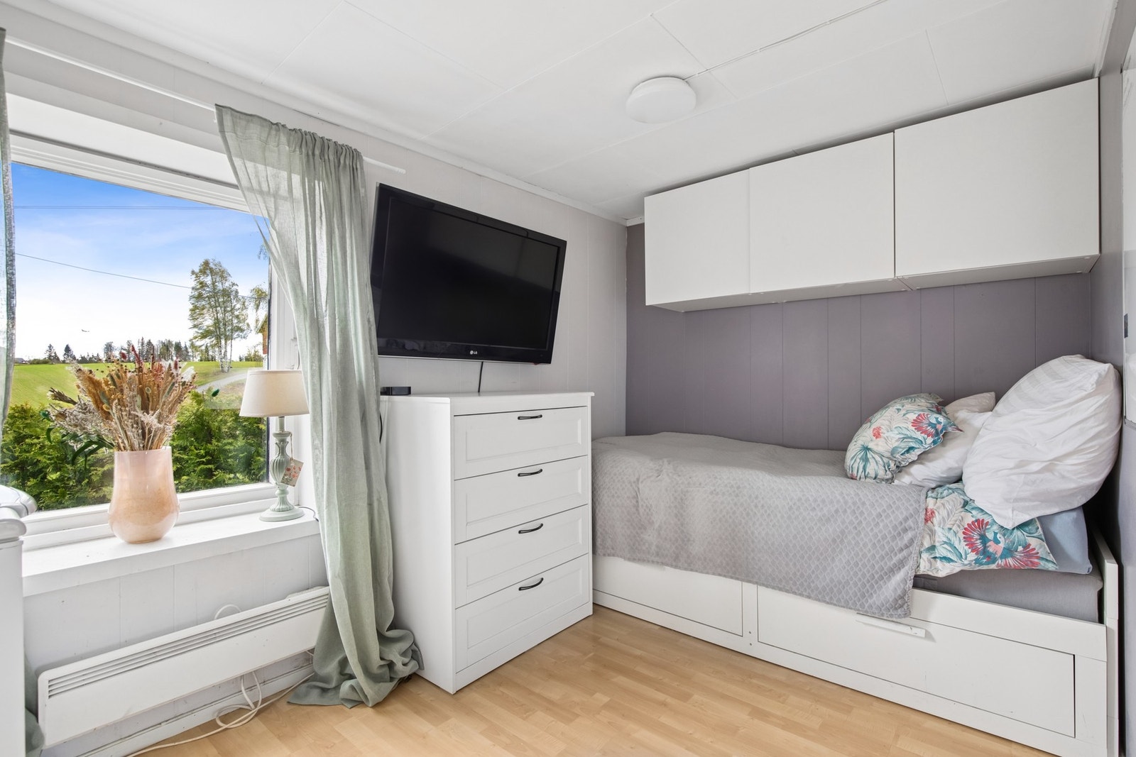 Det første soverommet har en praktisk og plassbesparende løsning med både overskap og skuffer under sengen. Vinduet slipper inn godt med dagslys og gir utsyn mot grønne omgivelser. Galleribilde