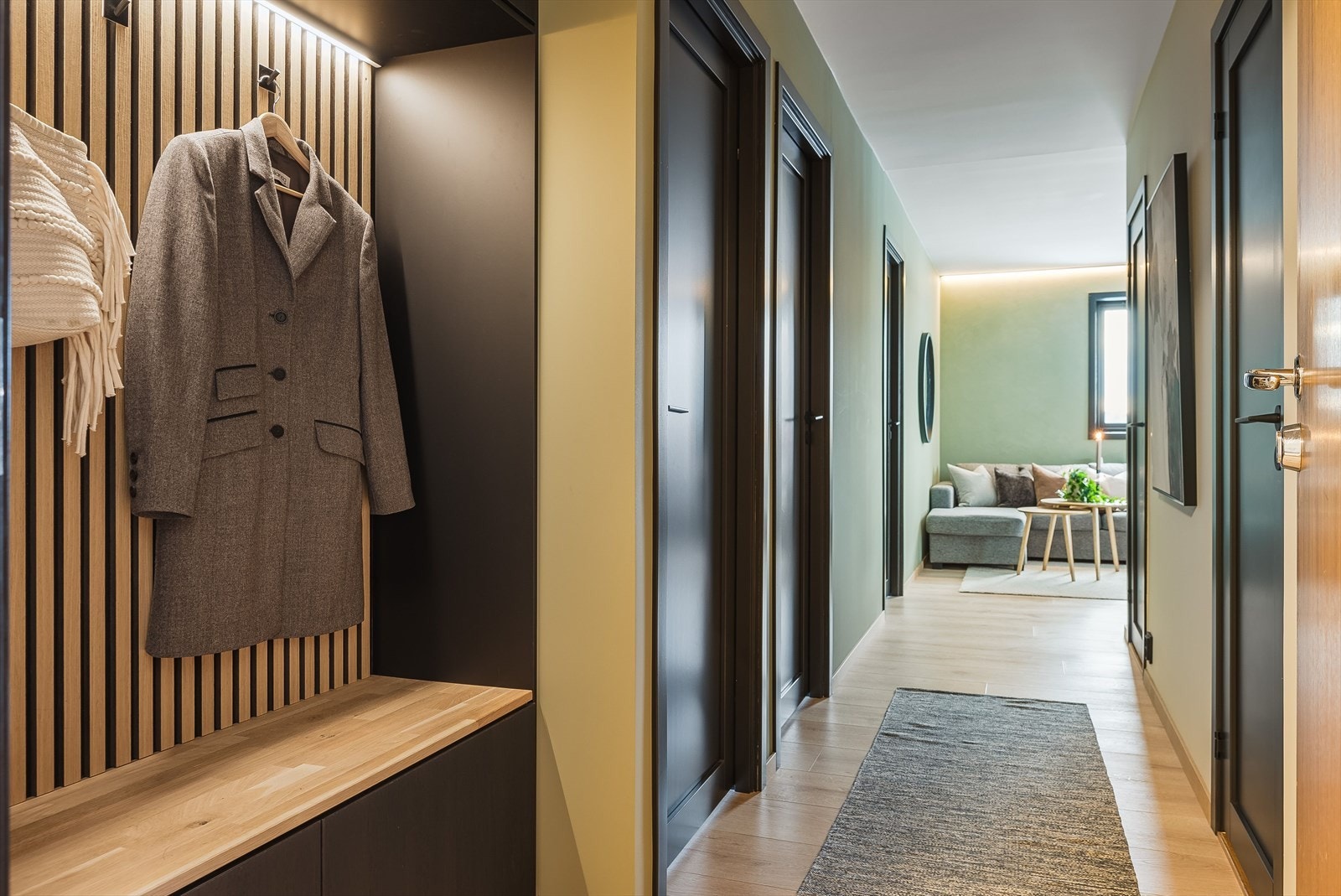 Når du entrer leiligheten får du umiddelbart et positivt inntrykk av denne svært gjennomførte og flotte leiligheten. I entréen er det en lekker garderobeløsning med sorte fronter, trespiler og LED-belysning. Galleribilde