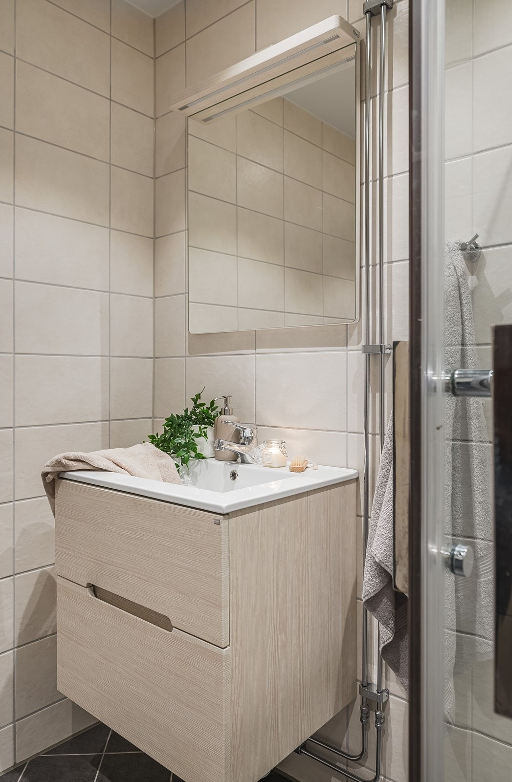 Flott baderomsinnredning fra 2024 med skuffer og heldekkende servant, speil med belysning over. Baderommet er også utstyrt med dusjhjørne med innfellbare glassdører, samt opplegg for vaskemaskin. Galleribilde