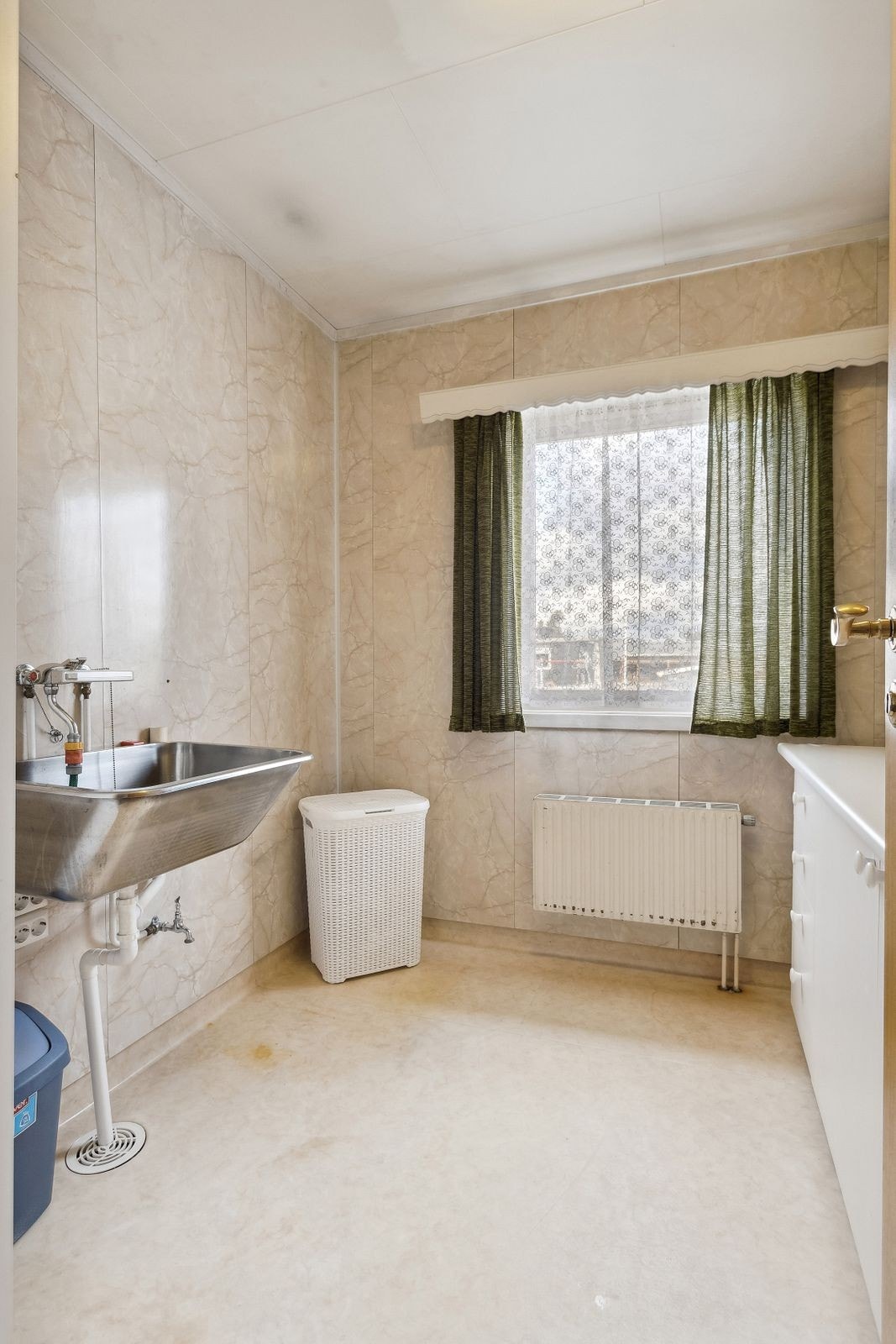 Vaskerom fra 1987 i 1. etasje med belegg på gulv, våtromsplater på veggene og vannbåren radiator. Rommet er utstyrt med lys innredning, utslagskum og opplegg for vaskemaskin. Galleribilde