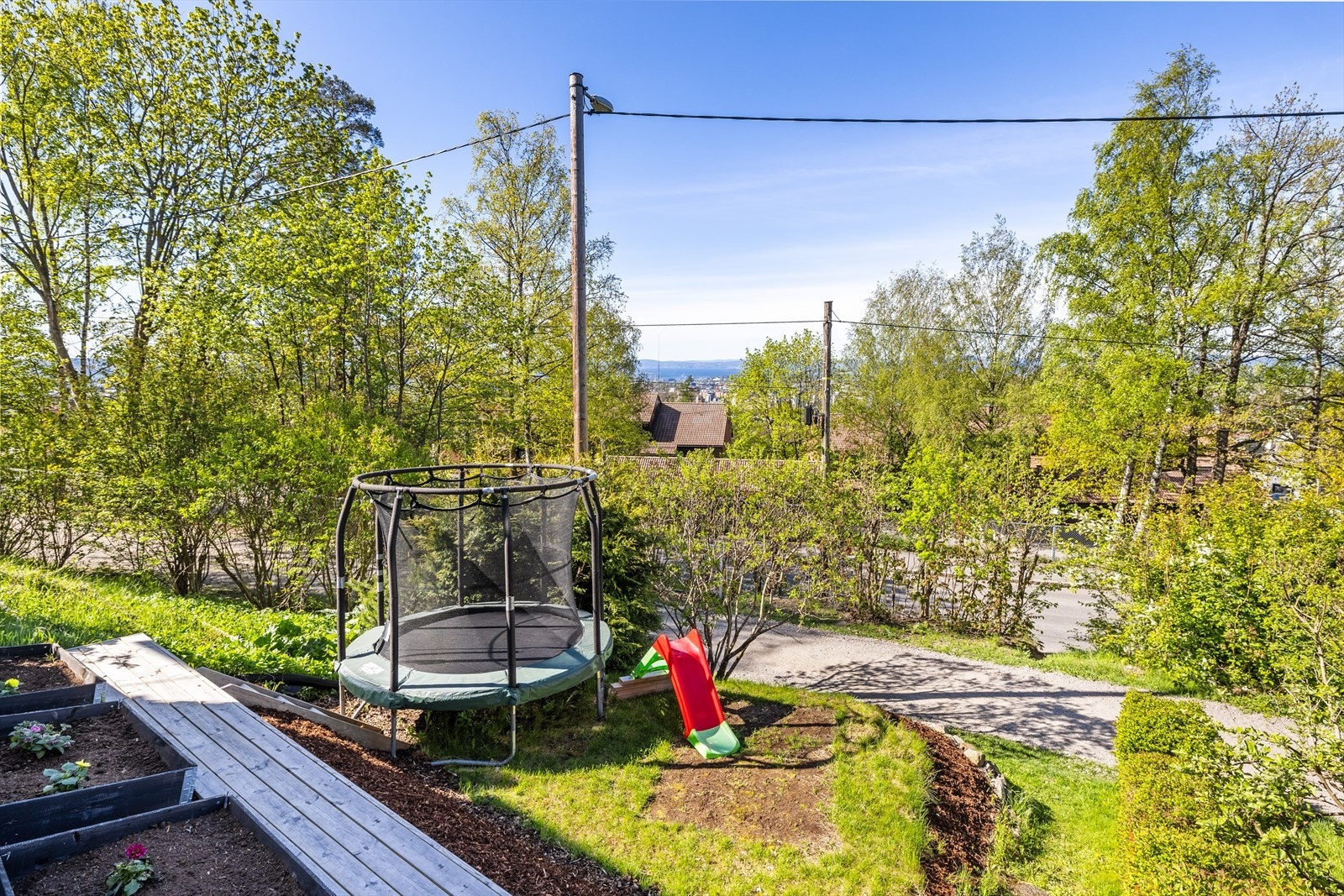 Nedenfor terrassen er en liten hage med bolomster- og urtekasser samt plass til trampoline. Gangveien nedenfor kjøres opp til skiløyper vinterstid. Galleribilde