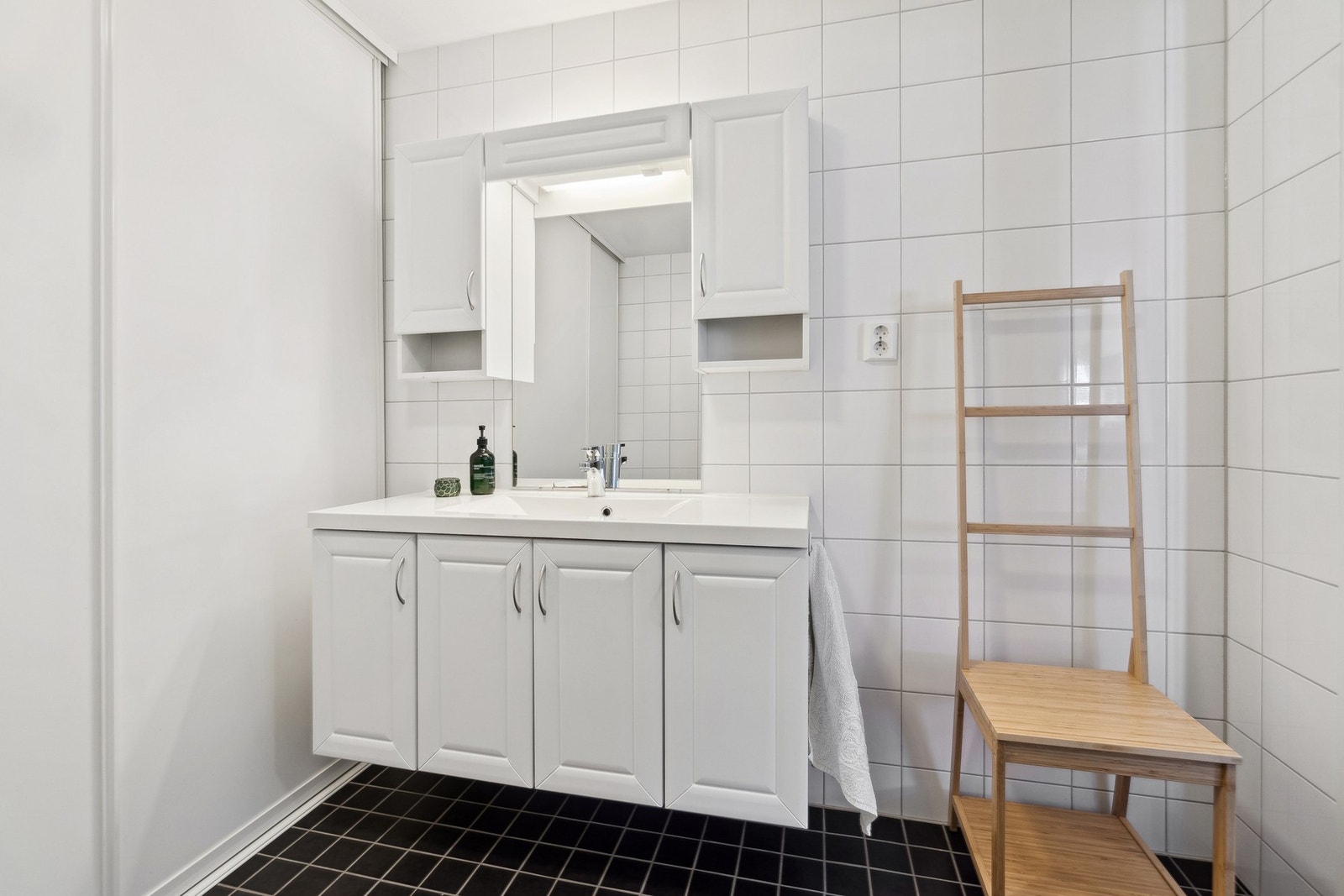 Like til høyre når du kommer inn i boligen finner du badet, som fremstår tidløst med sorte gulvfliser mot hvite overflater. Galleribilde