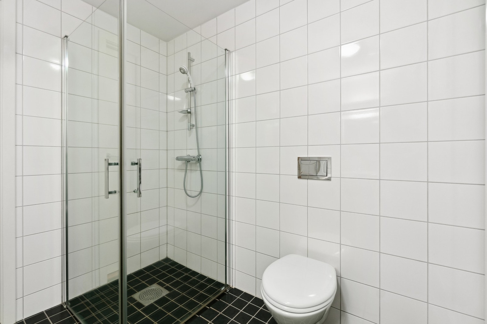 Badet har øvrig vegghengt toalett, servantskap og dusjhørne med glassdører. Galleribilde