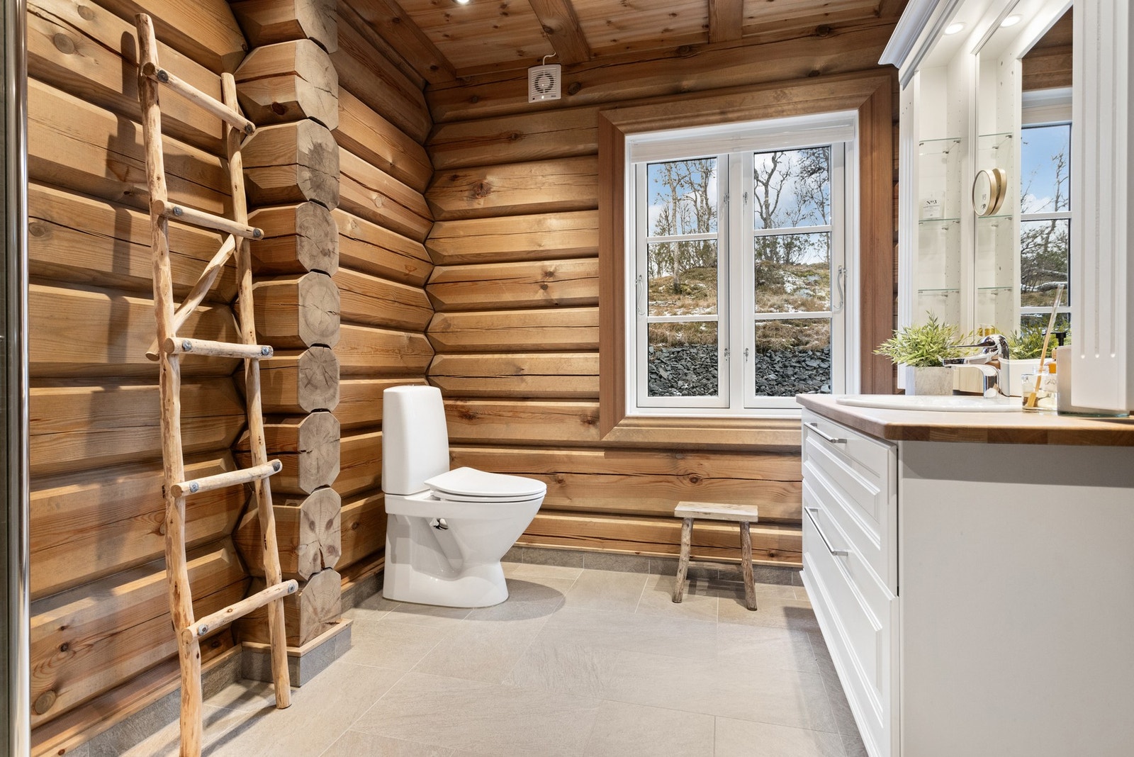 Pent bad med lekre fliser på gulv og i dusjnisje som mot de røffere tømmerveggene skaper et flott, moderne stil Galleribilde