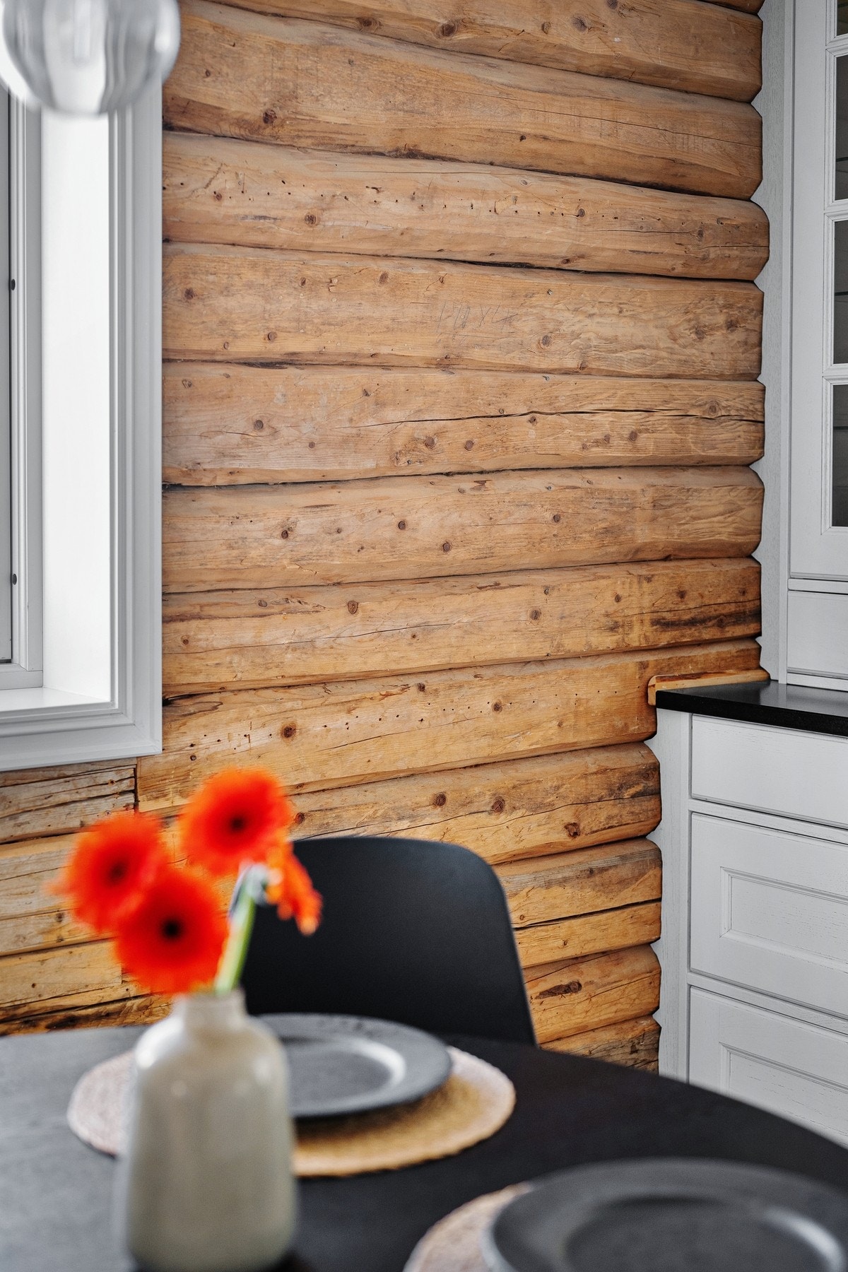 En vegg med laftet tømmer står i fin kontrast til alt det moderne - og gir ekstra liv til kjøkkenet. Galleribilde