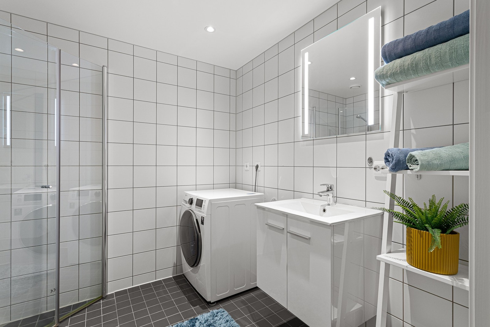 Speil med integrert lys over servant og opplegg for vaskemaskin. Galleribilde