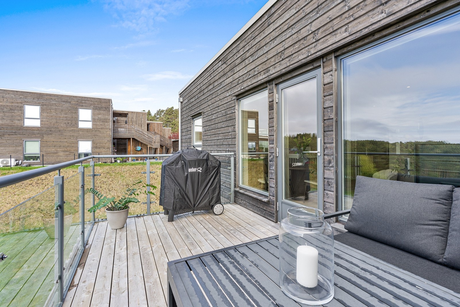 Balkongen har moderne rekkverk i glass- og aluminium, terrassebord og lys/strømuttak. Galleribilde