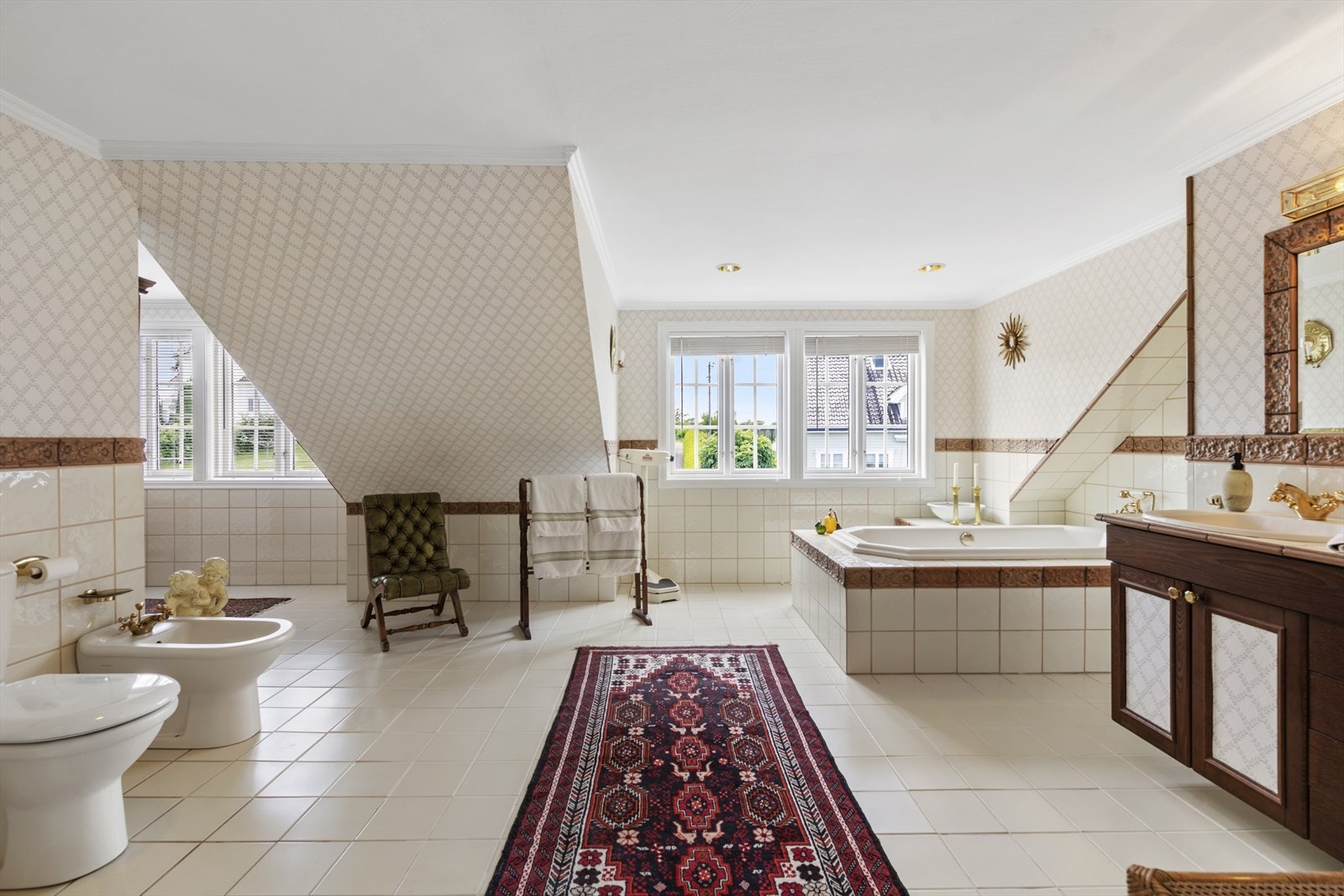 Det store badet i andre etasje har fliser på gulv og deler av vegg, downlights og innredning med dobbel servant. Galleribilde