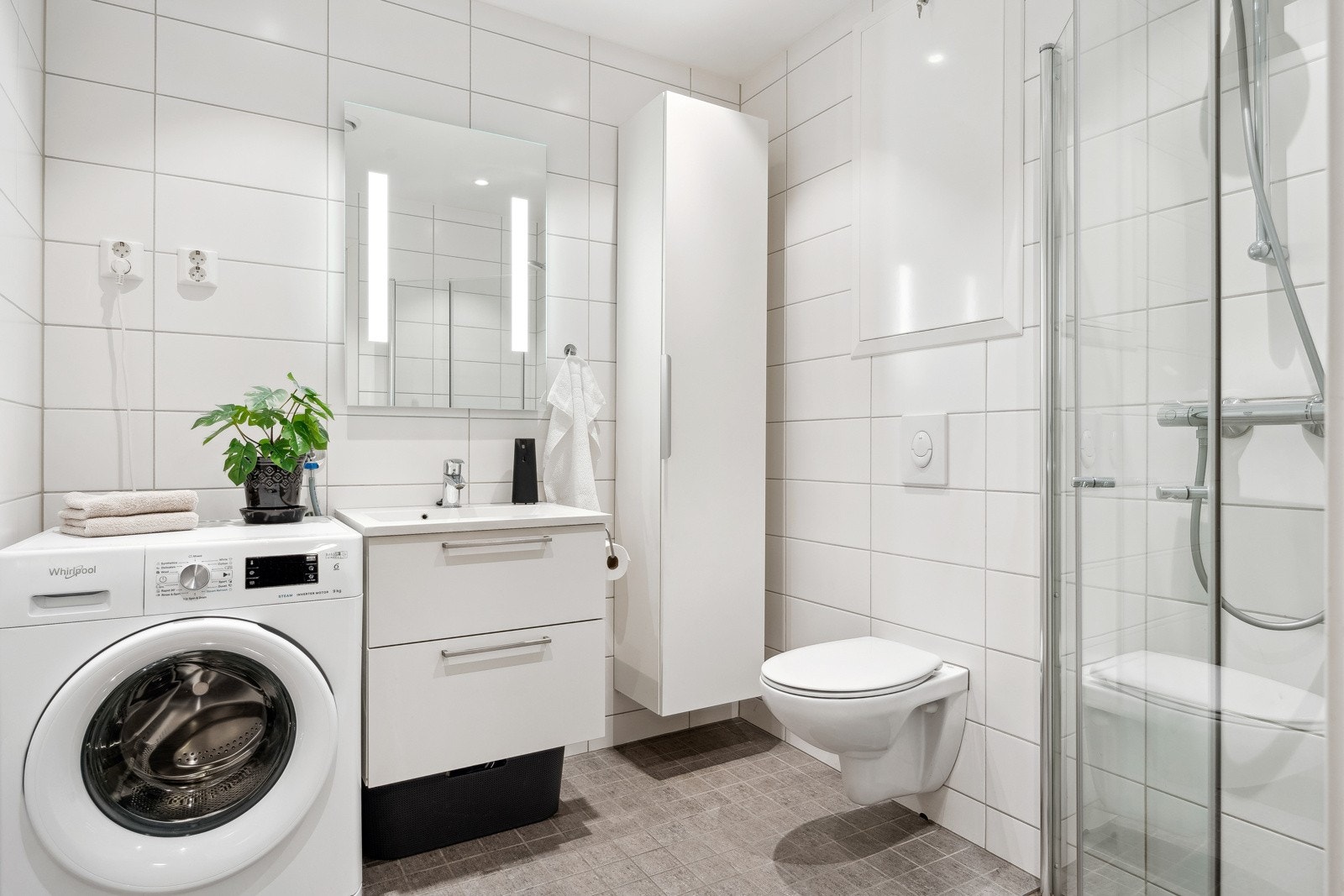 Pent flislagt baderom med moderne innredning og innfellbare dusjdører i glass. Galleribilde