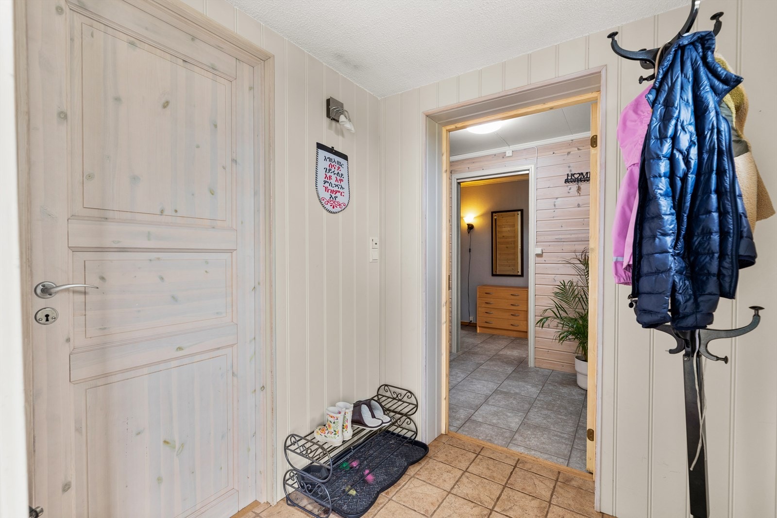 Entréen i underetasjen har flislagt gulv og lyse overflater, med plass til oppbevaring. Galleribilde