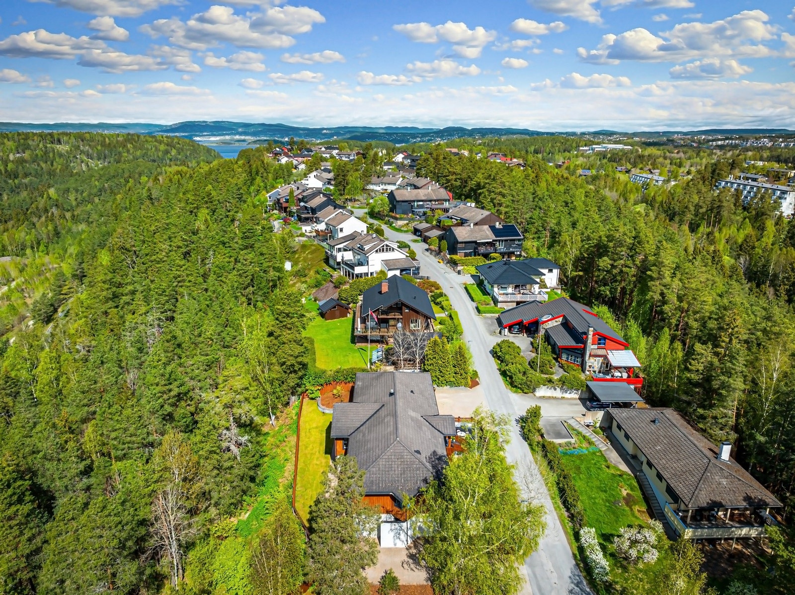 Stor inngjerdet hage med gressplen på begge sider av huset. Galleribilde