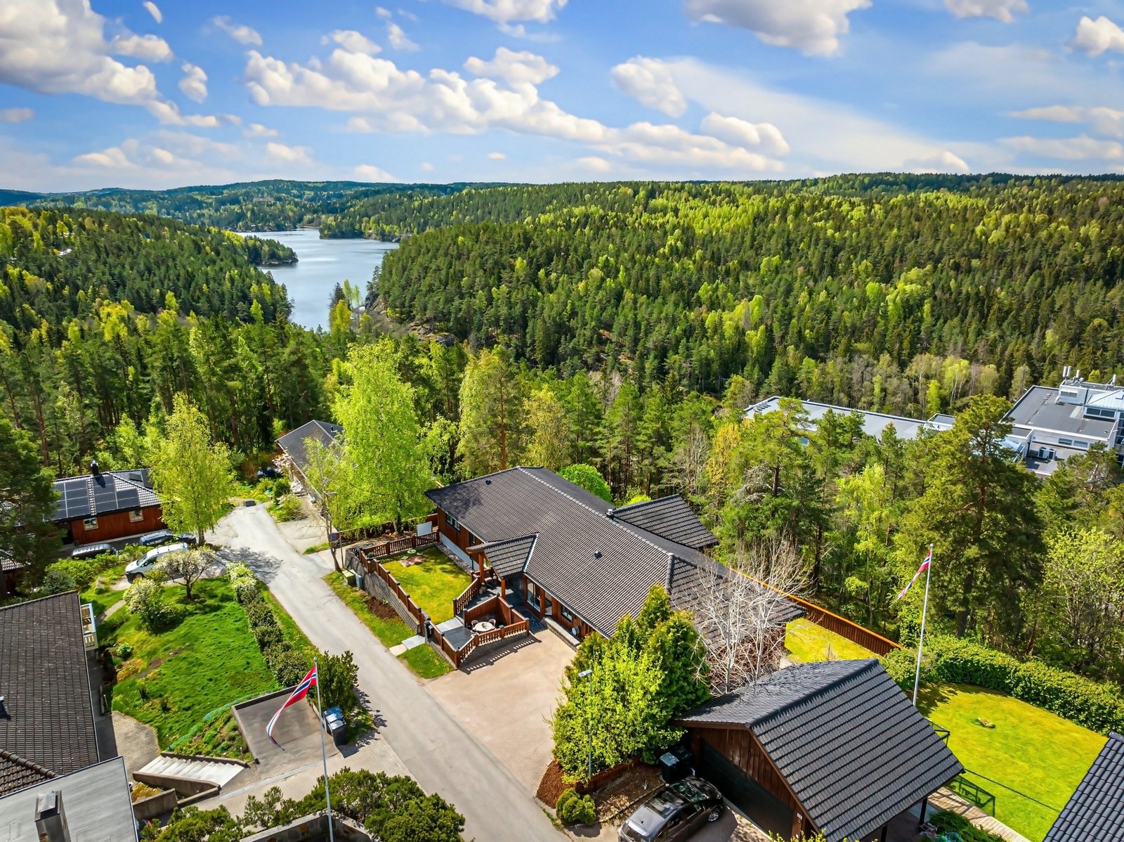 Opparbeidet tomt med innkjørsel og parkeringsområder med beleggningsten, hagearealer på begge sider av huset. Galleribilde