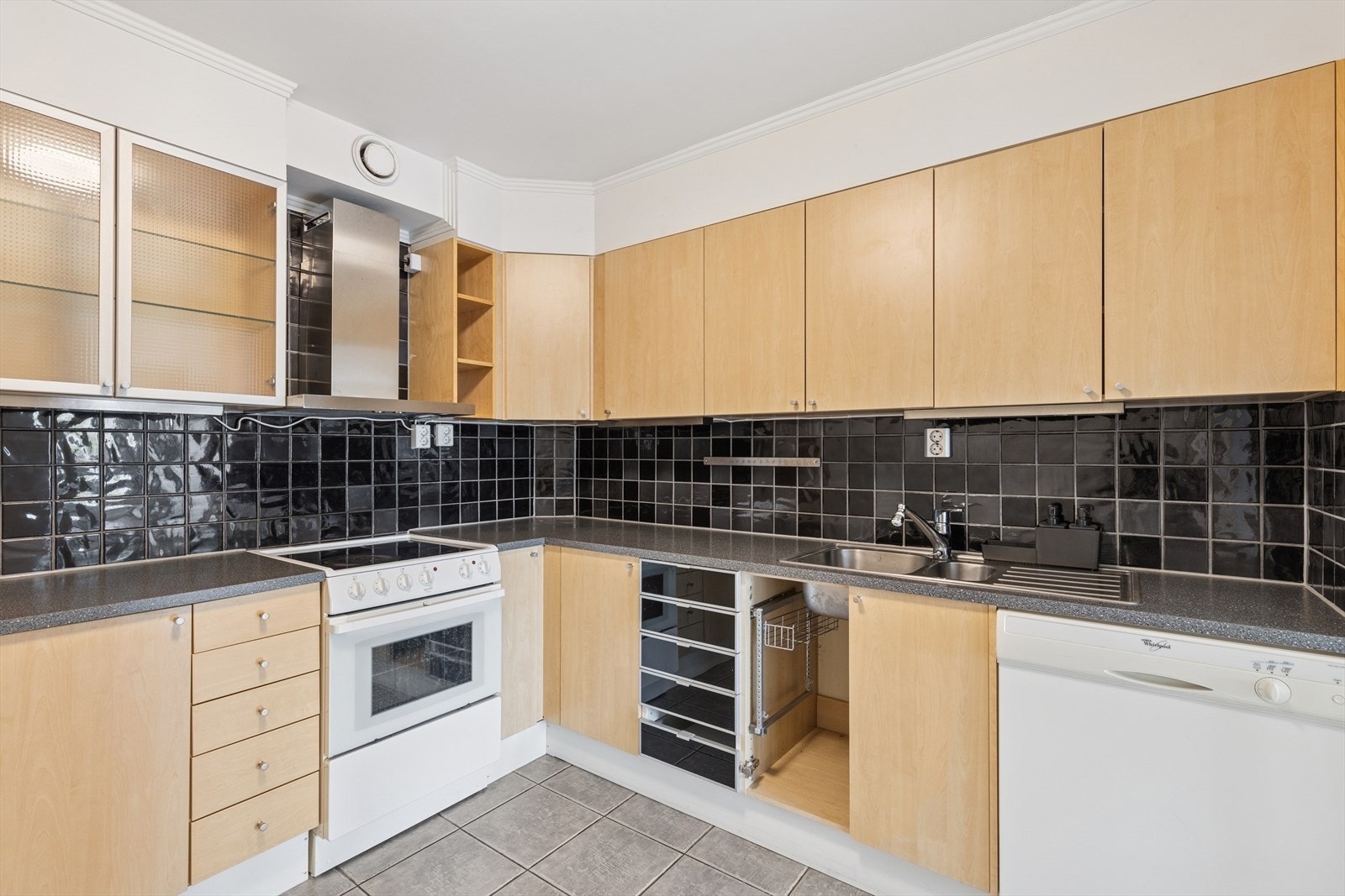 Det er foring mellom overskap og himling, laminat benkeplate, fliser over benken, lys under overskap, kullfilterventilator med stål hette og stål benkebeslag. Galleribilde