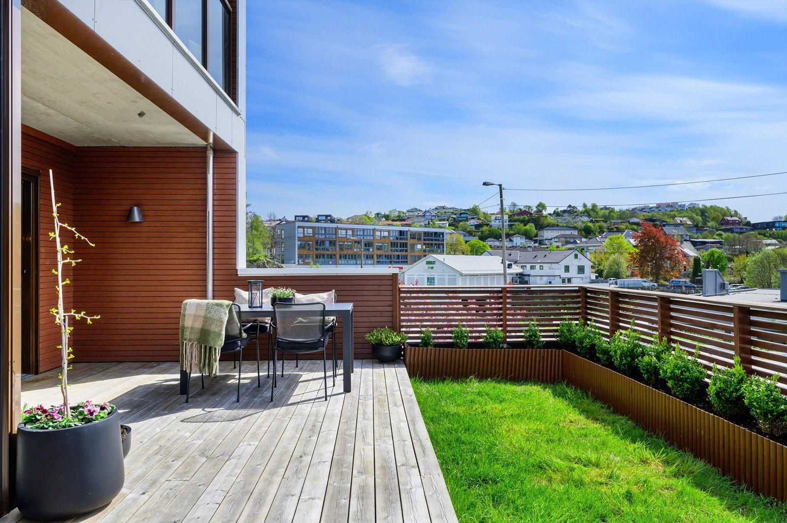 Pent opparbeidet med terrassebord, plen og stor blomsterkasse. Galleribilde