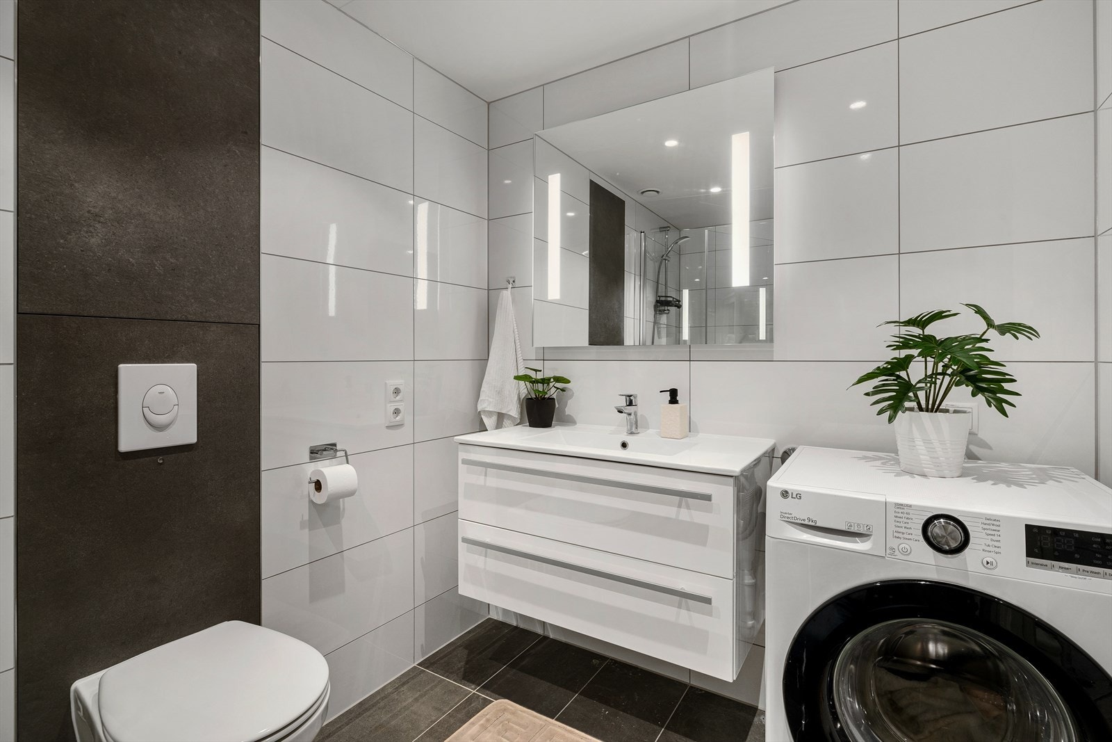 Rommet har innredning med nedfelt servant, veggmontert toalett, dusjhjørne, speil m/lys og opplegg for vaskemaskin. Galleribilde