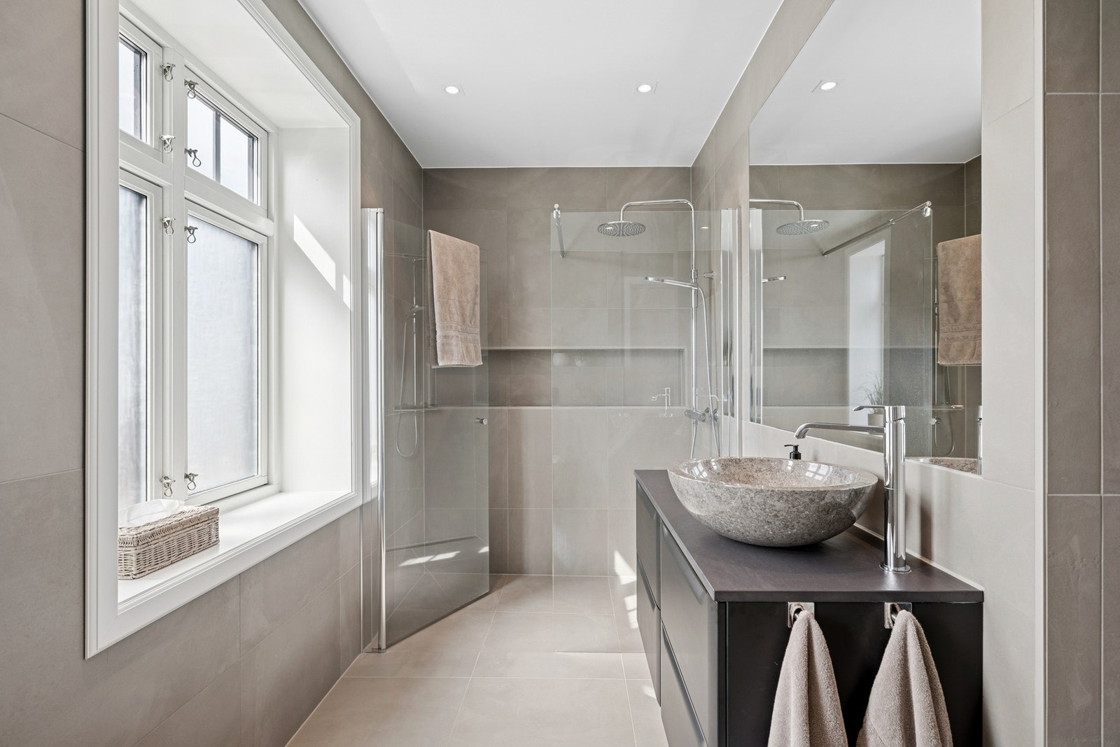 Lekkert baderom med regnfallsdusj, eksklusive materialvalg og gjennomført fargepalett. Galleribilde