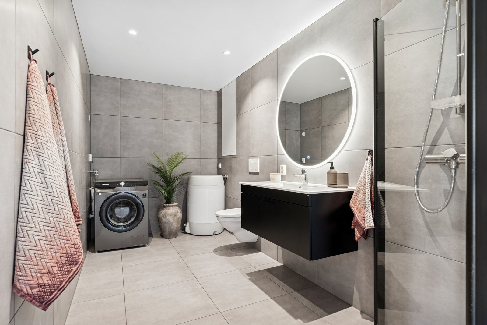 Delikat flislagt baderom med 60x60 fliser og opplegg til vaskemaskin og tørketrommel Galleribilde