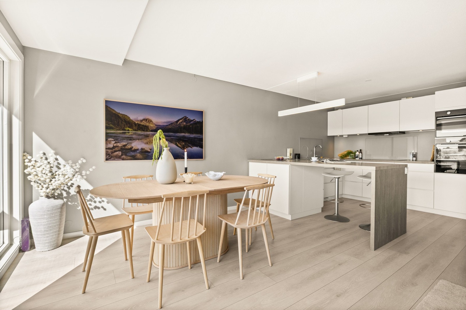 Kvik kjøkkeninnredning fra 2017 med hvite glatte fronter, integrerte håndtak/grep og laminerte benkeplater. Galleribilde