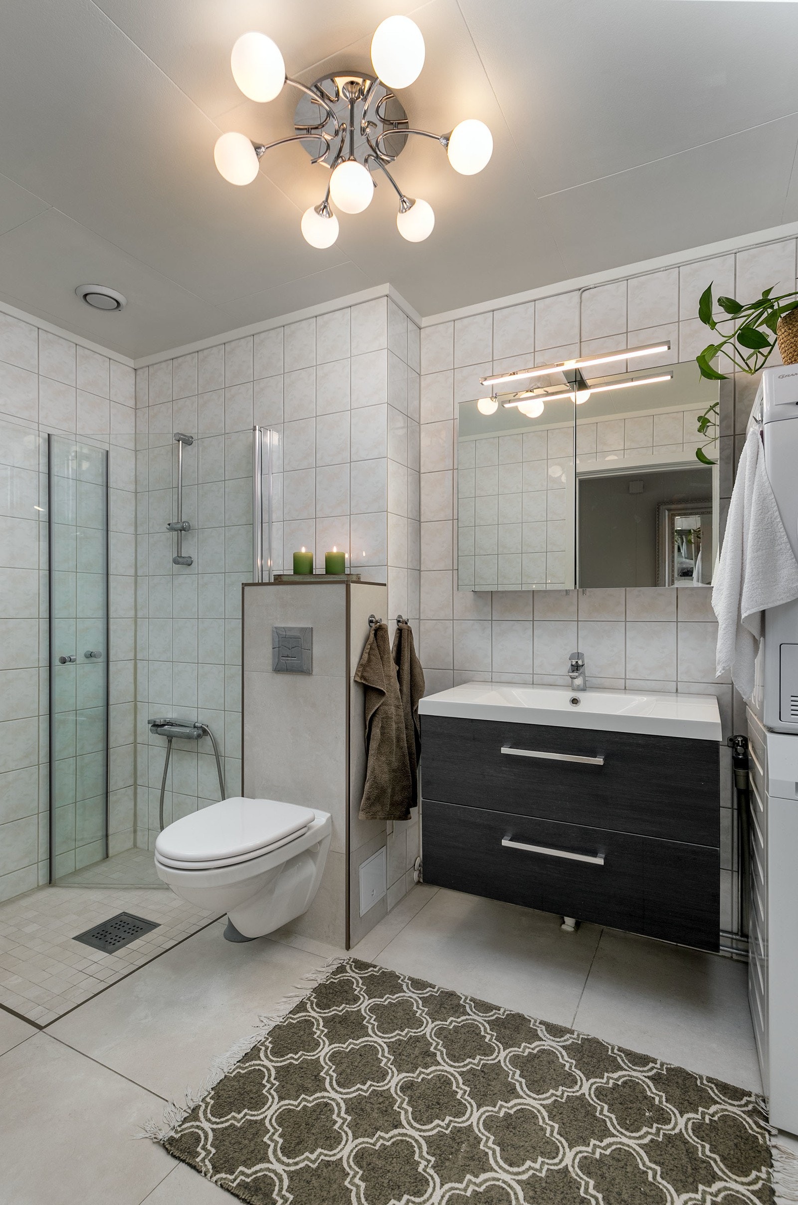 Moderne skuffeinnredning med servant, samt speil med belysning over servant. Videre har badet dusjhjørne med innfellbare dører og vegghengt toalett. Badet er gitt TG2 på pkt. om overflater, vanntett sjikt og sluk. Galleribilde