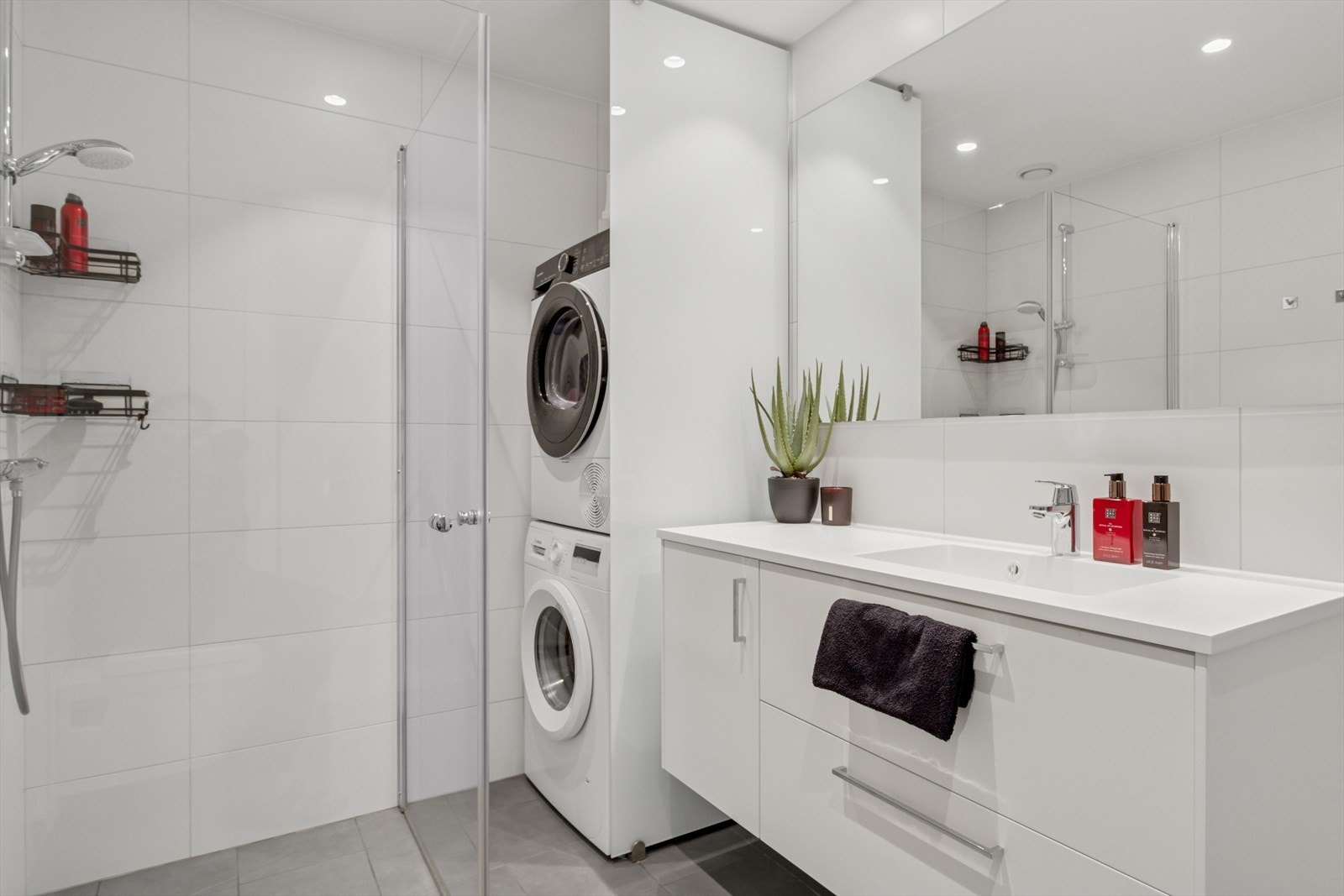 Badet er utstyrt med servant med underskap, vegghengt toalett, dusjhjørne og opplegg for vask/tørk. Galleribilde