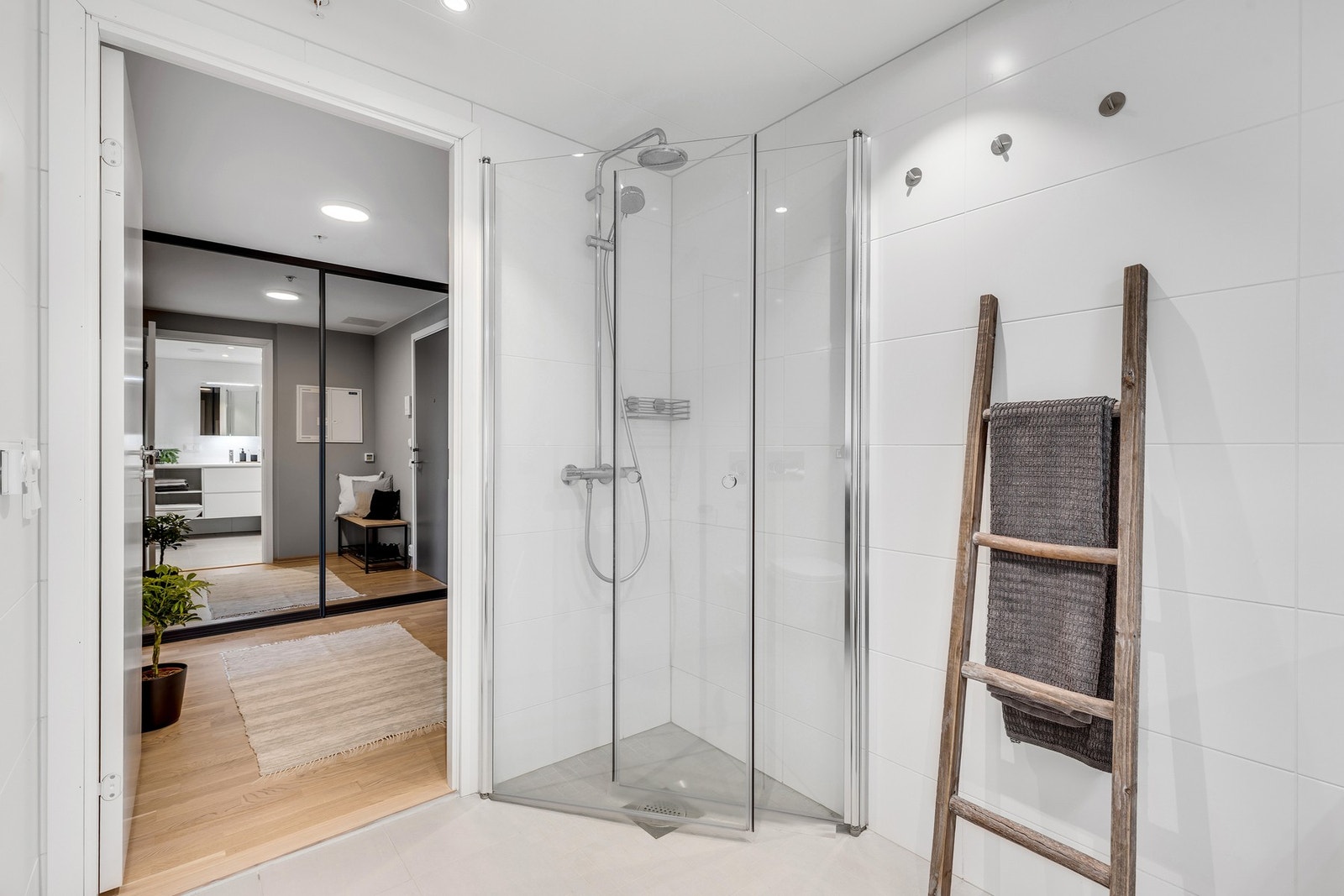 Badet er innredet med innfellbare dusjvegger i glass, veggmontert WC, kran og avløp for vaskemaskin, servant på underskap og speil. Badet er i underkant av 5 kvm og har en praktisk utnyttelse av arealet. Galleribilde