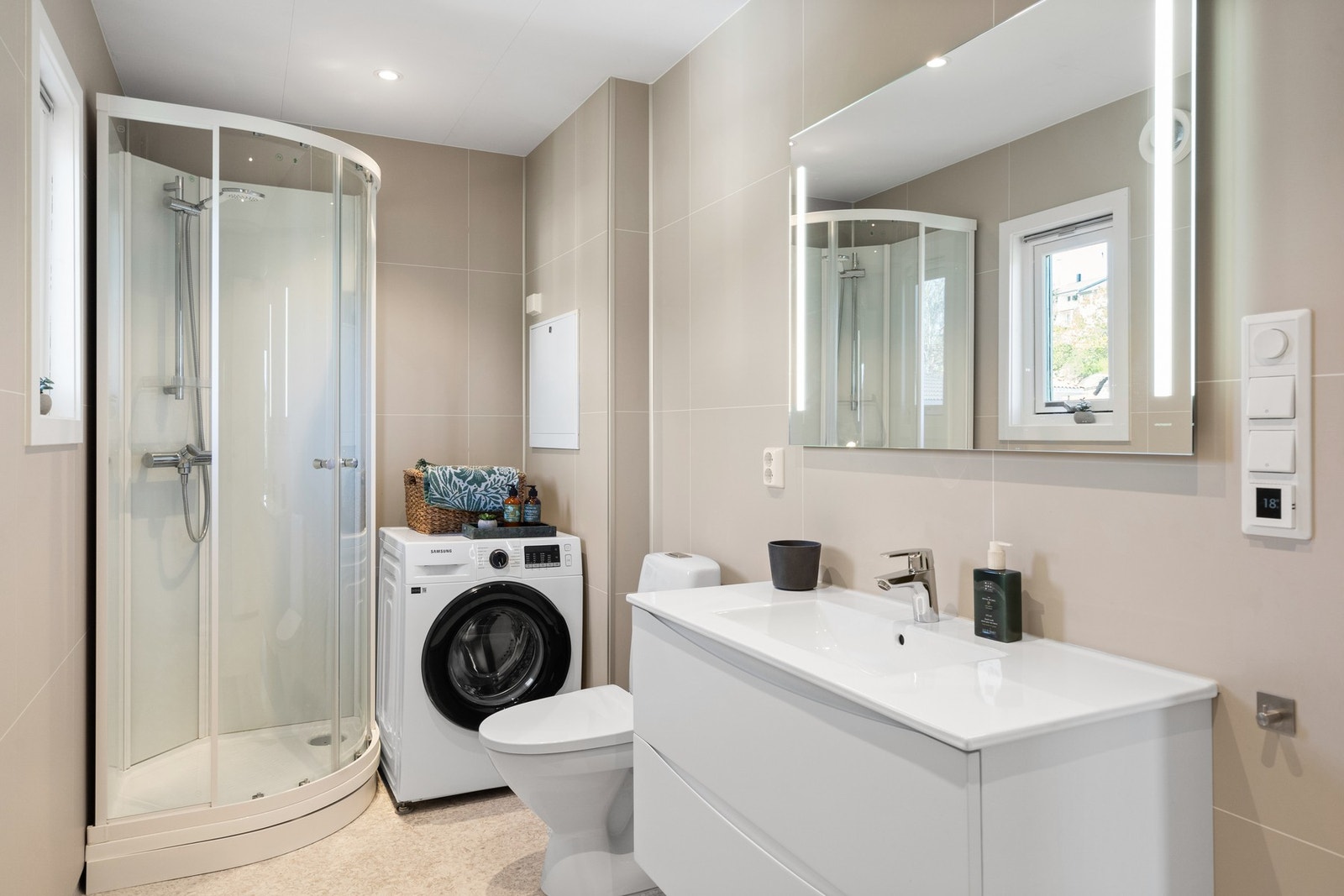 Lyst og pent bad med innredning, wc, dusj og opplegg for vaskemaskin Galleribilde