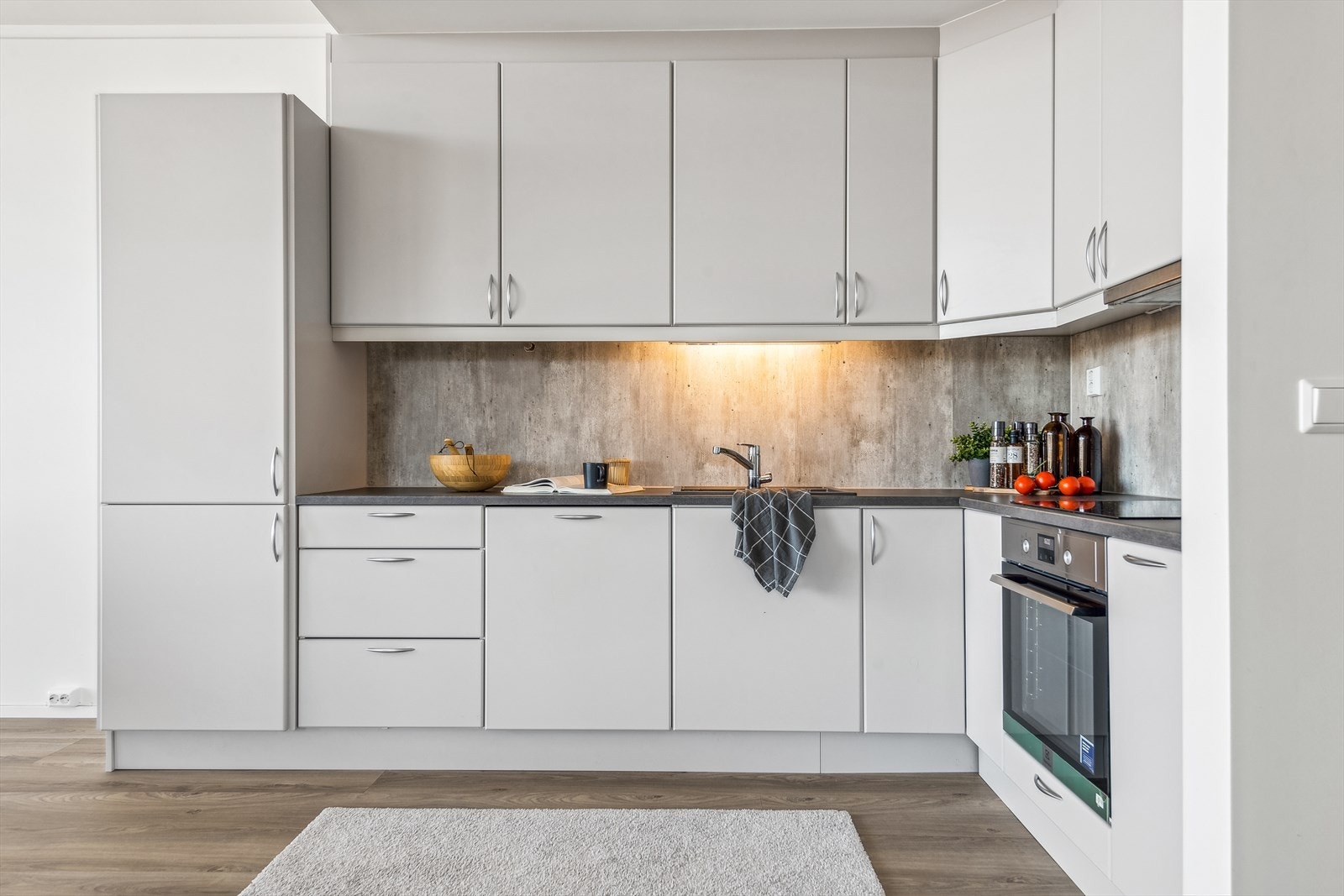 Kjøkken i åpen løsning mot stue. Innredning i slette fronter med laminat benkeplate. Galleribilde