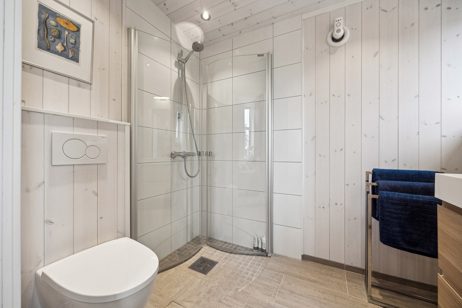 Bad nr. 2 består av speil, servant med oppbevaringsseksjon, veggmontert toalett og dusjhjørne. Galleribilde