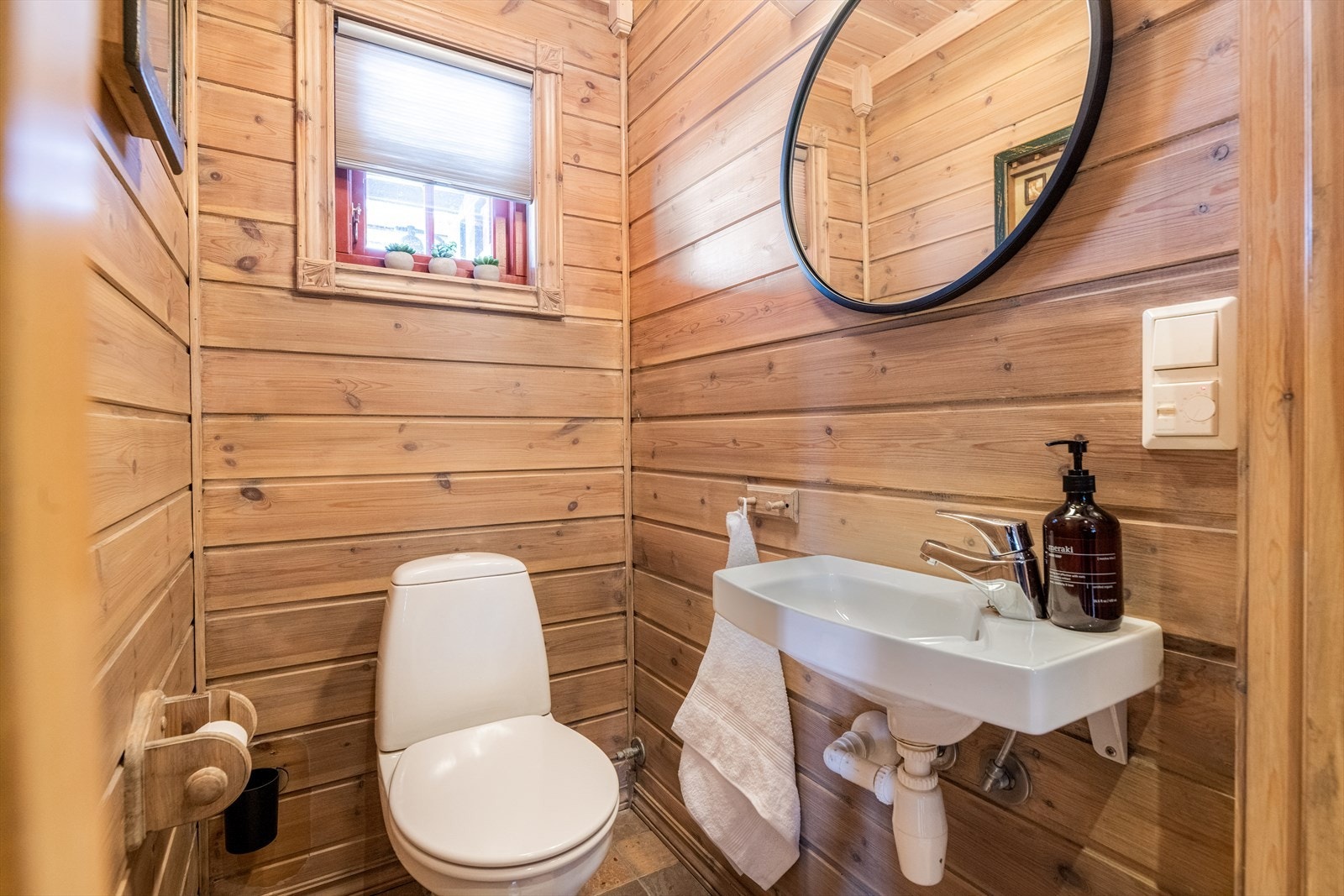 Hytta har i tillegg et adskilt toalettrom hvor det er flis på gulv med varmekabler, og trepanel på vegger og i himling. Her er det håndvask montert på vegg og et gulvmontert toalett. Galleribilde