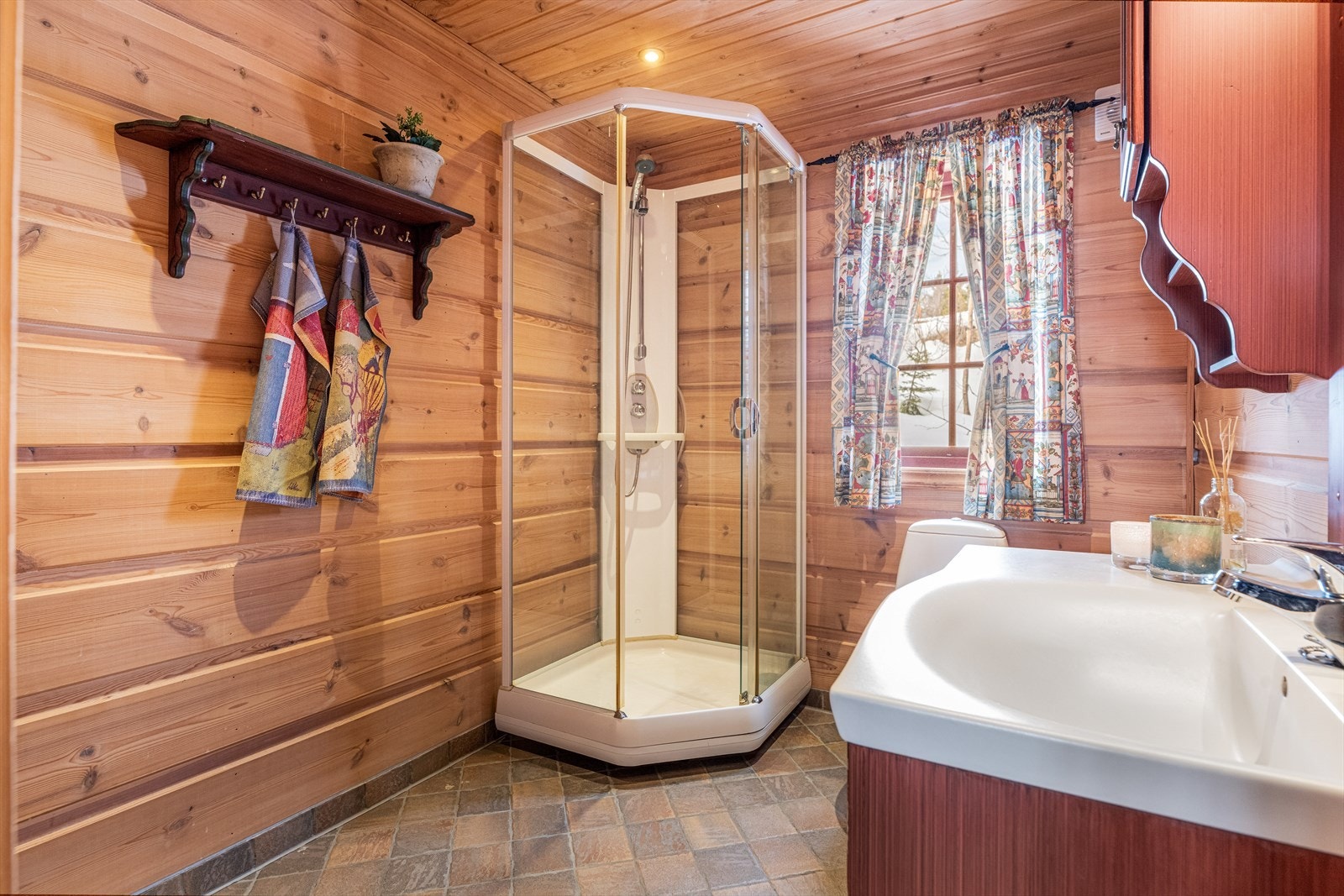 Baderomsmøblement med profilerte fronter i malt utførelse som passer fint inn i hytta. Nedfelt servantplate, god speilflate og belysning over vask. Videre har rommet gulvmontert toalett og dusjkabinett. Galleribilde