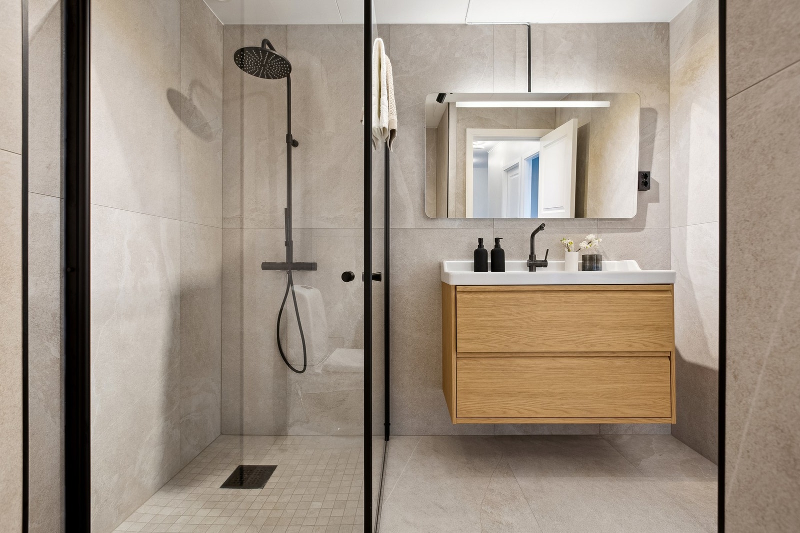 Badet er delikat og praktisk innredet med vegghengt servant med oversepeil Galleribilde