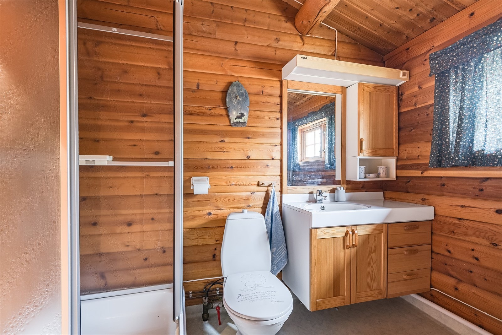 Baderommet er utstyrt med innredning med servant, speil med belysning og vegghengt skap over, dusjkabinett og gulvstående toalett. Galleribilde