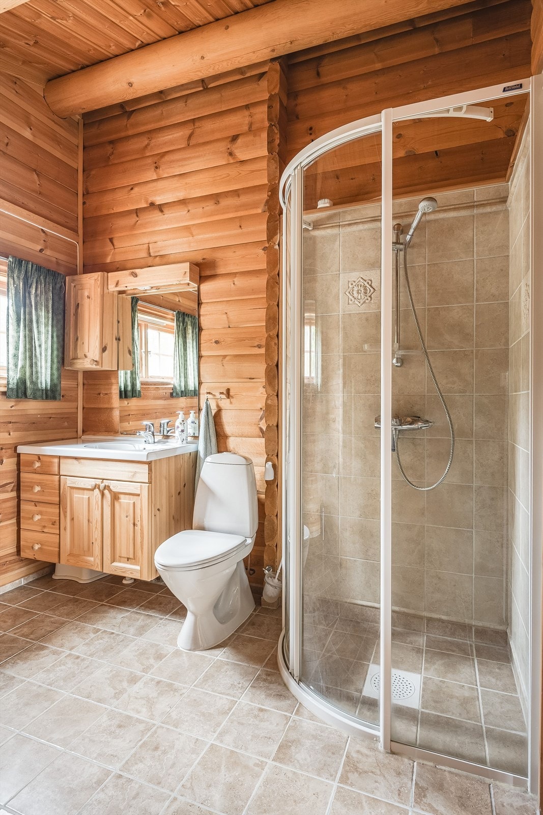 Baderommet er utstyrt med baderomsinnredning med servant, speil med belysning og vegghengt skap over, dusjhjørne og gulvstående toalett. Galleribilde