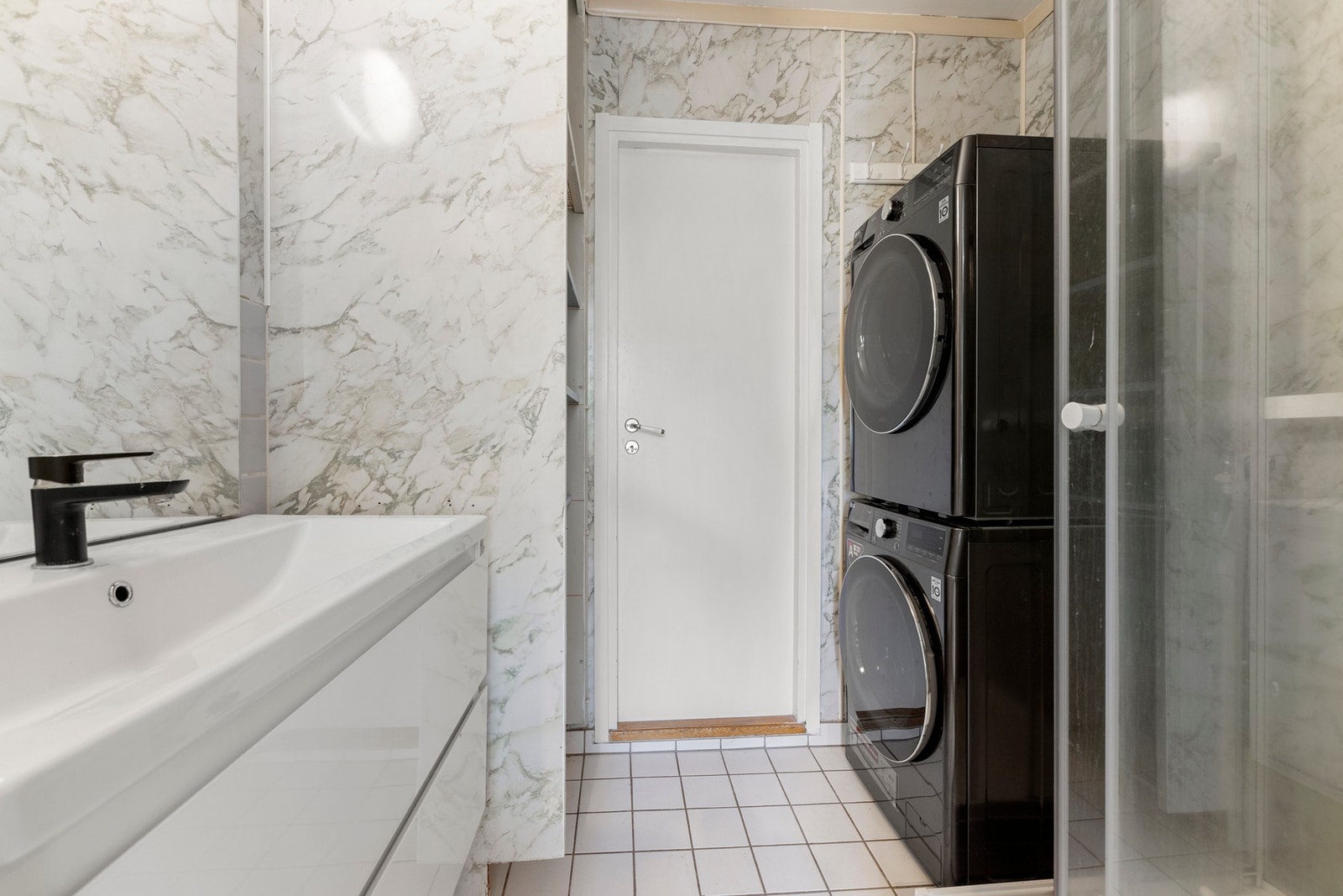 Badet er funksjonelt innredet med dusjkabinett, vegghengt servant og opplegg for vaskemaskin. Galleribilde