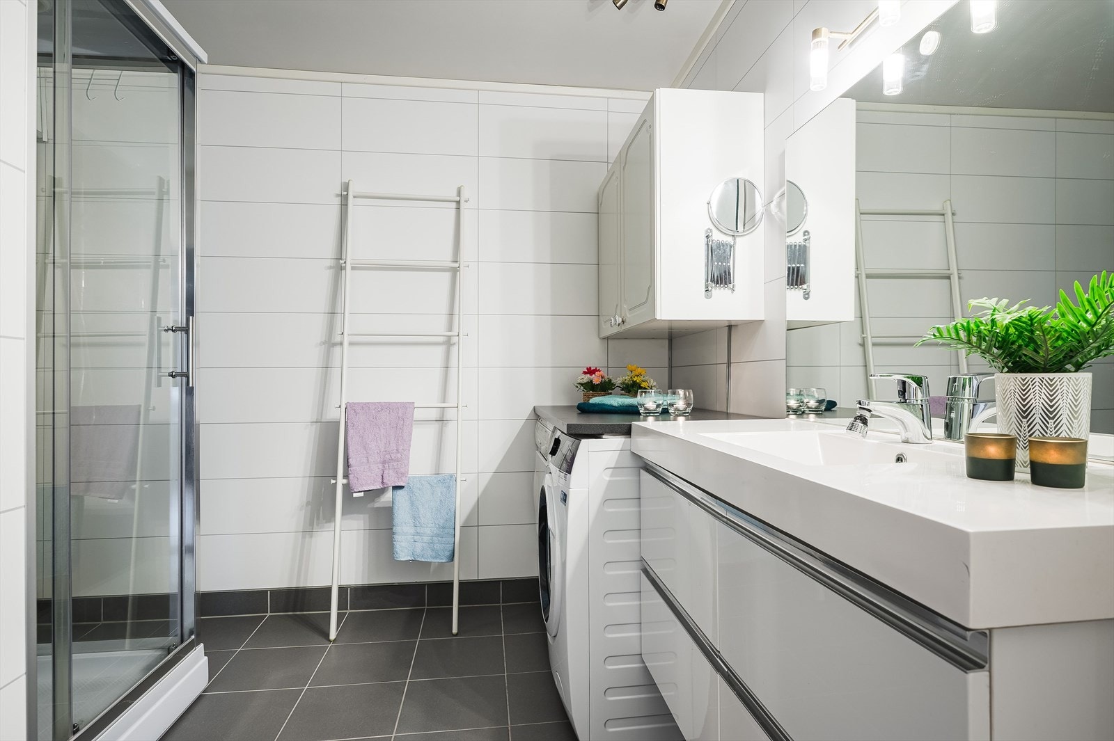 Leiligheten har et lyst baderom som ble utvidet og oppusset i 2014. Baderommet har grå fliser på gulv og lyse våtromsplater på veggene. Galleribilde