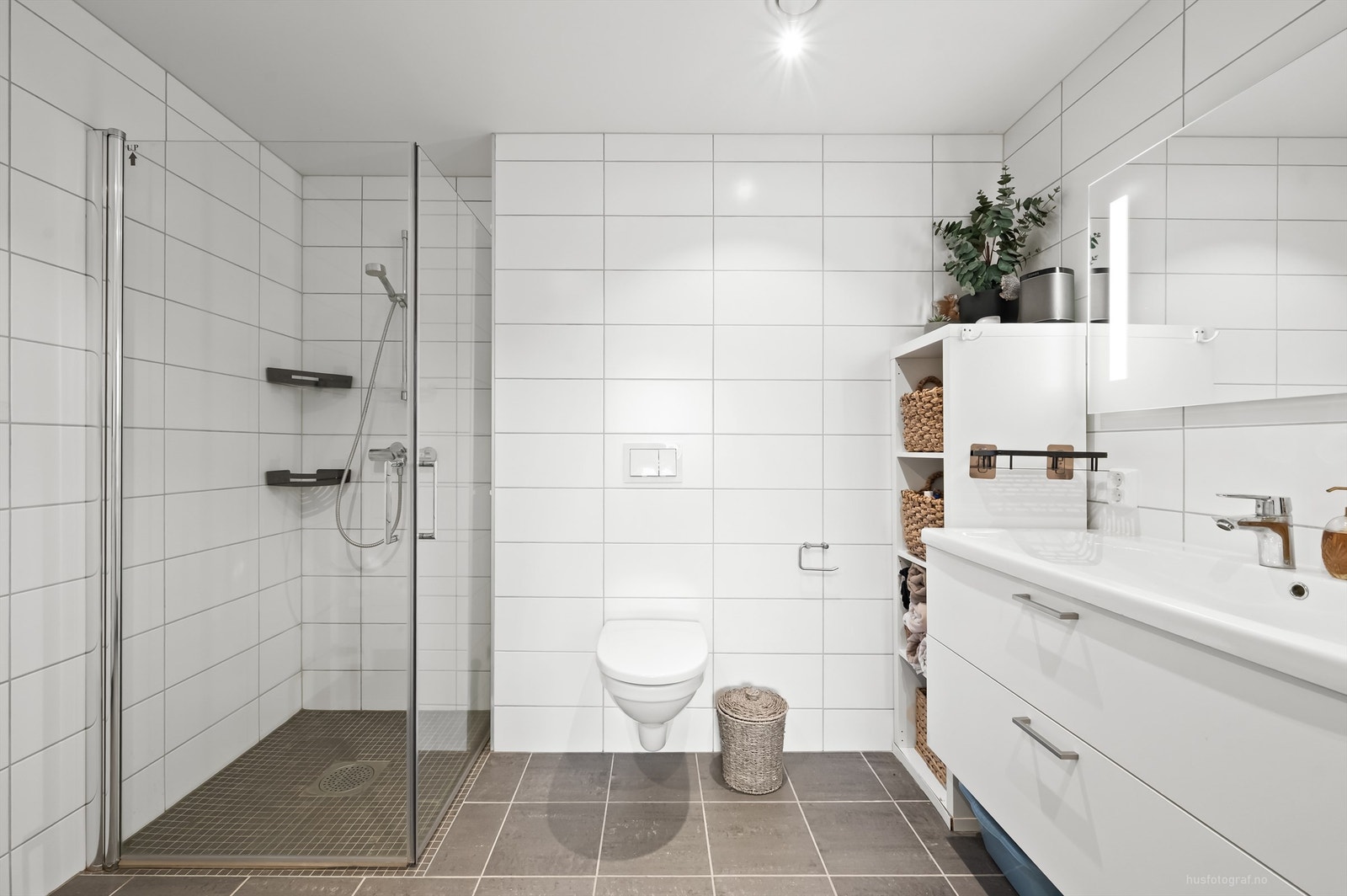 Badet har dusjhjørne med foldedører av glass Galleribilde