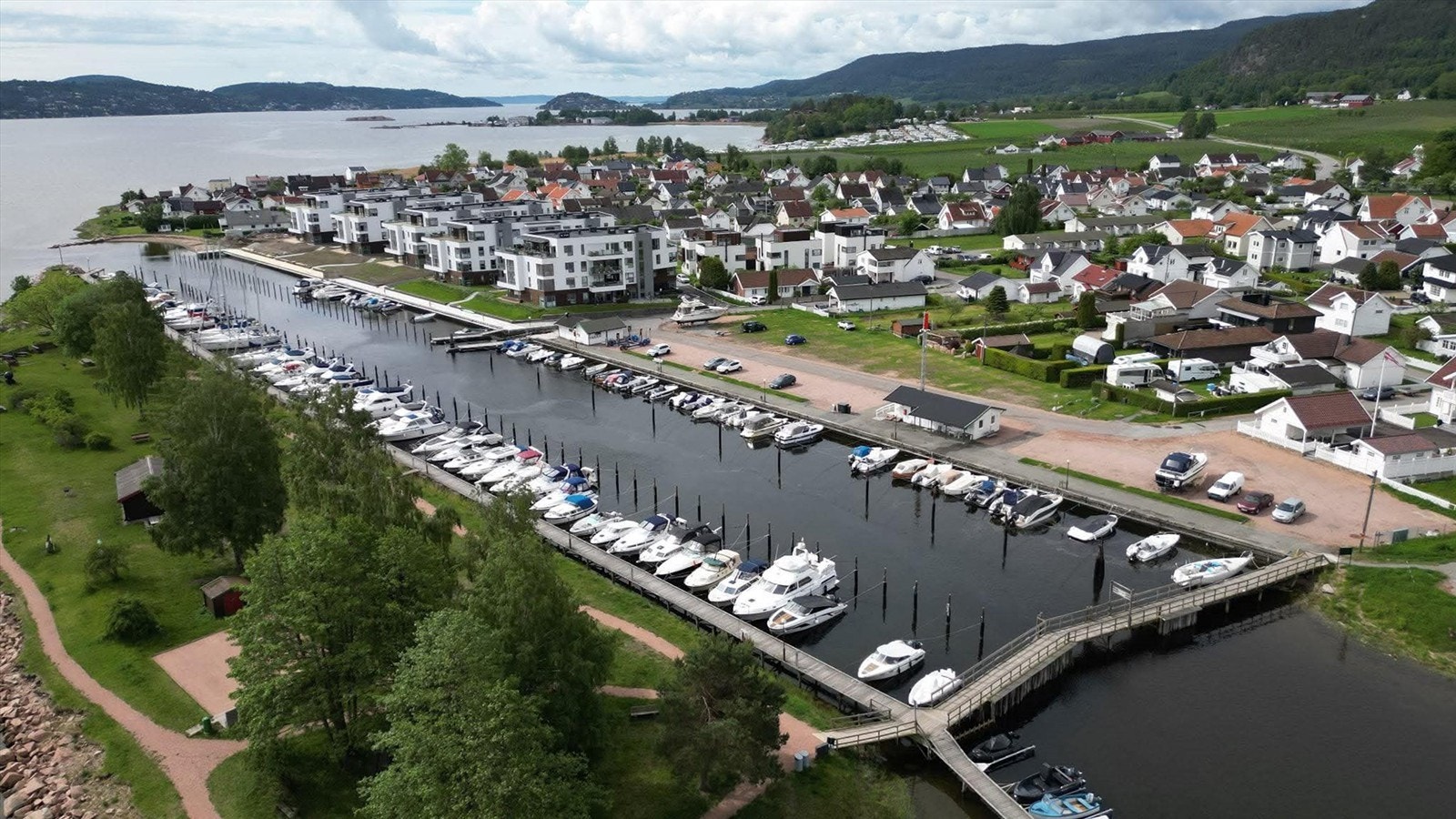 Arkivfoto - Foran bygningene er det etablert en sammenhengende fjordpromenade med småbåthavn og badeplass med sandstrand Galleribilde
