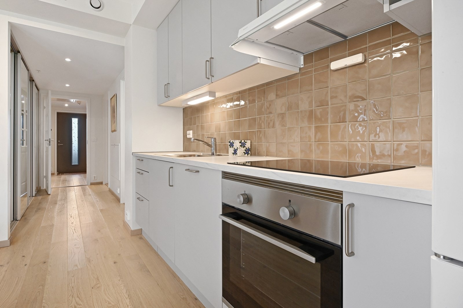 Kjøkken med oppvaskmaskin og komfyr. Det er koketopp, ventilator og løst kjøkken som medfølger. Galleribilde