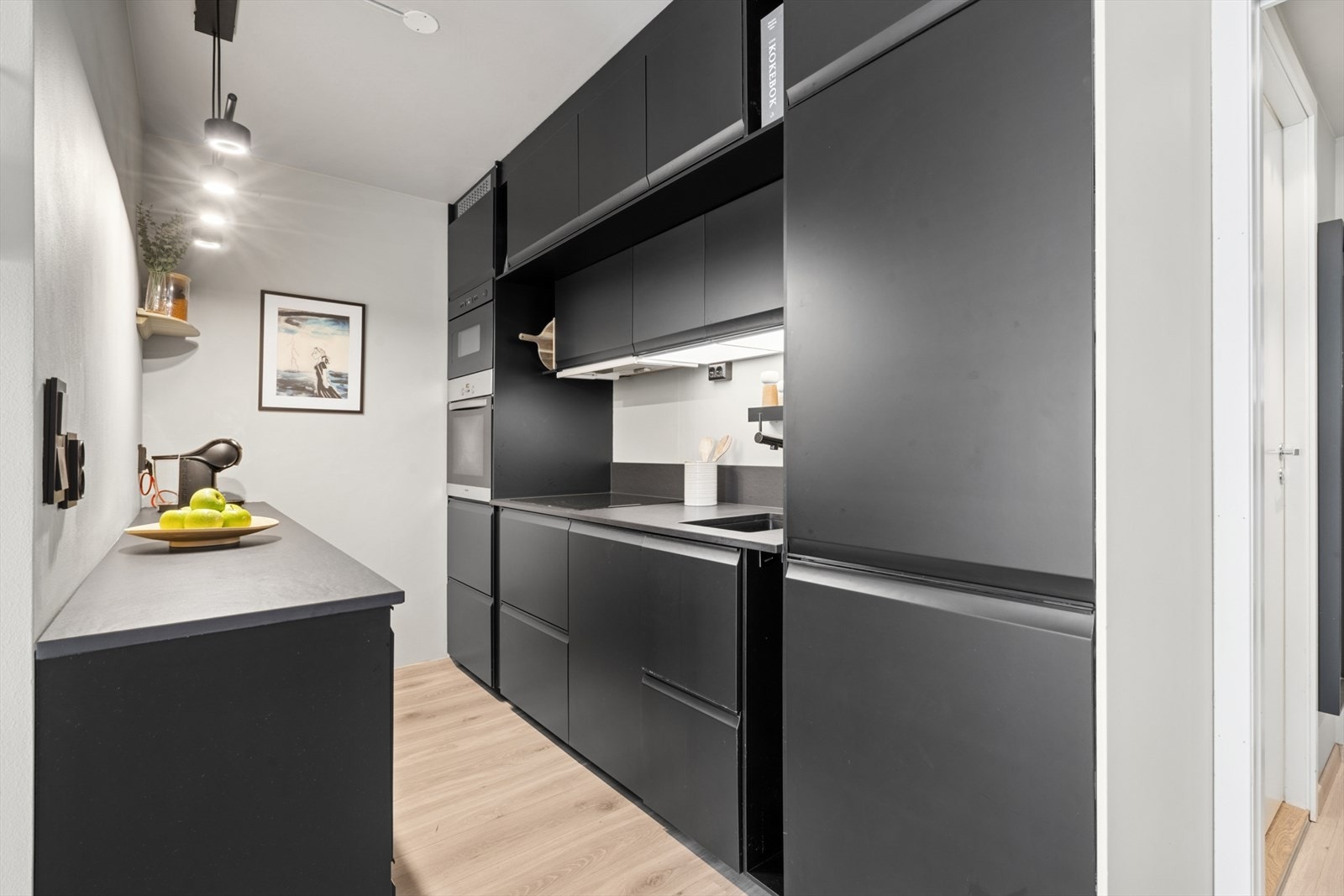 Kjøkkenet er fra IKEA (2023), og mikroovnen ble byttet ut i 2023. Benkeplater i keramikk er fra Nerostein og tåler høy varme. Mekanisk avtrekk og ventilator. Galleribilde